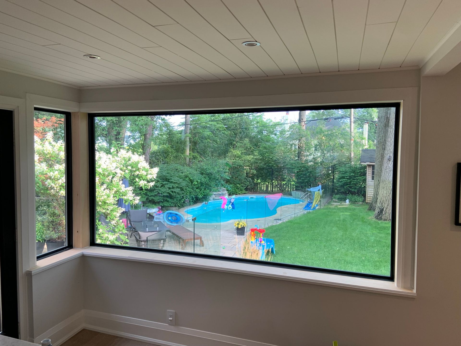There is a large window with a view of a pool in the backyard.