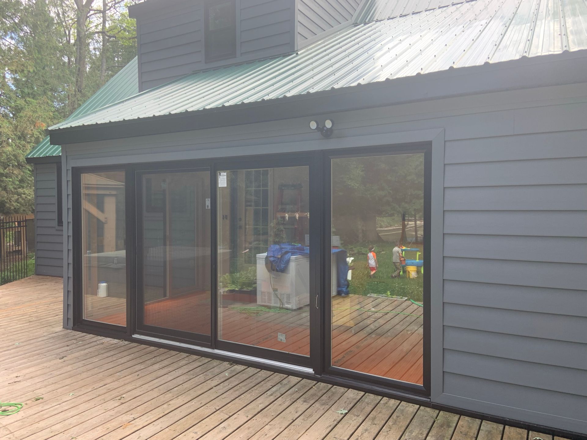 A gray house with a green roof and sliding glass doors
