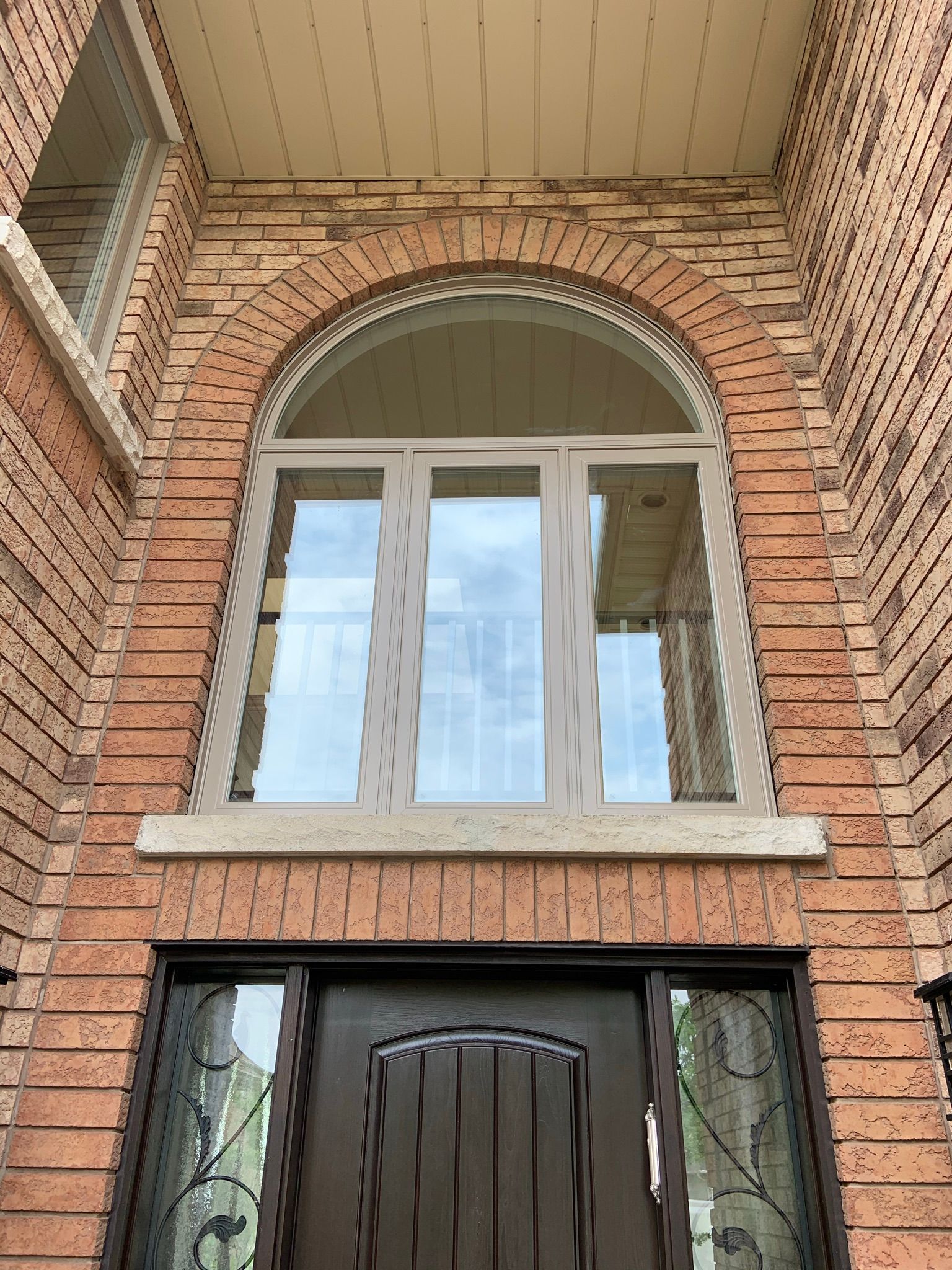 A brick building with a large arched window and a door.