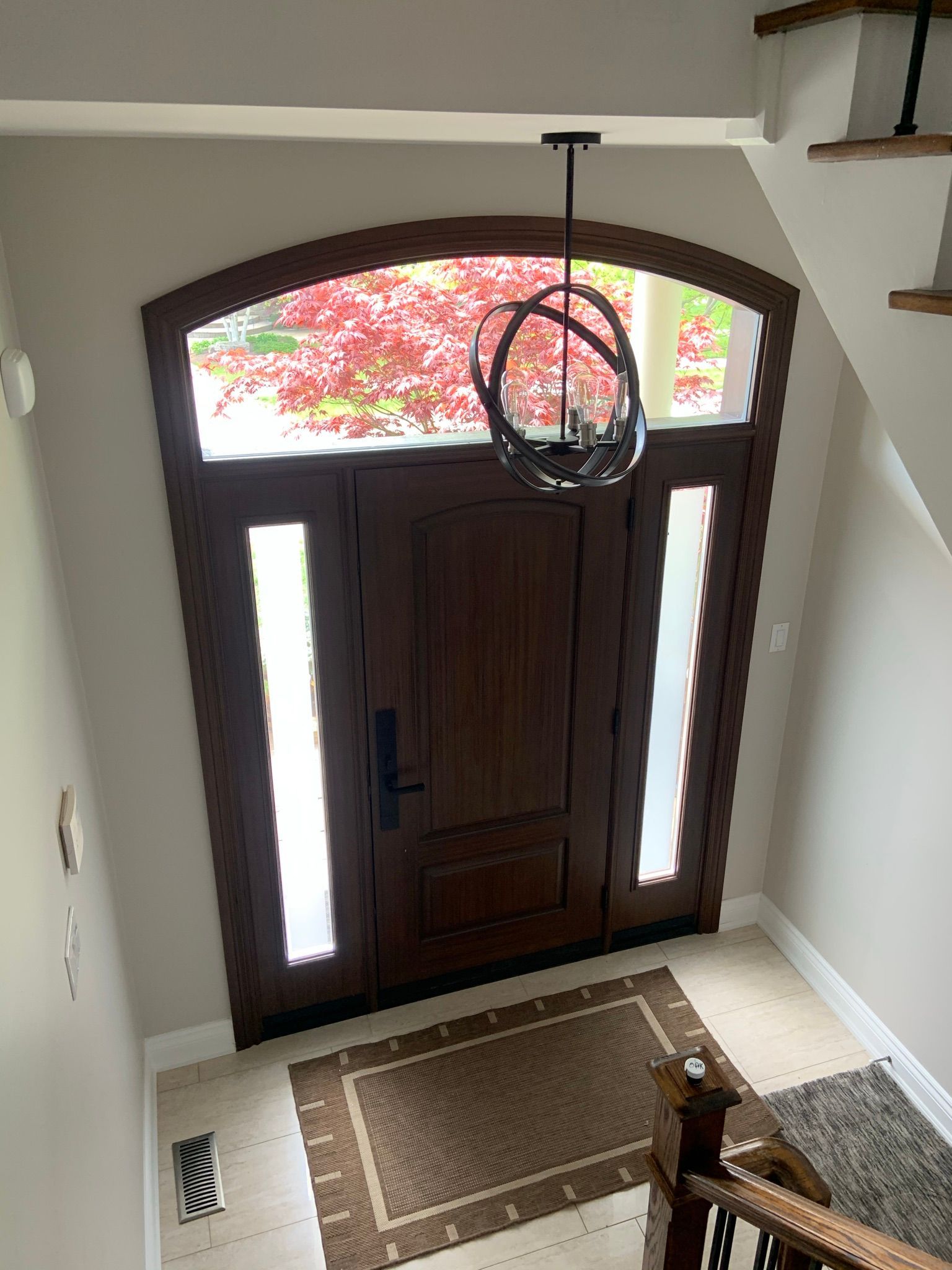 A large wooden door with a chandelier hanging from the ceiling in a hallway.