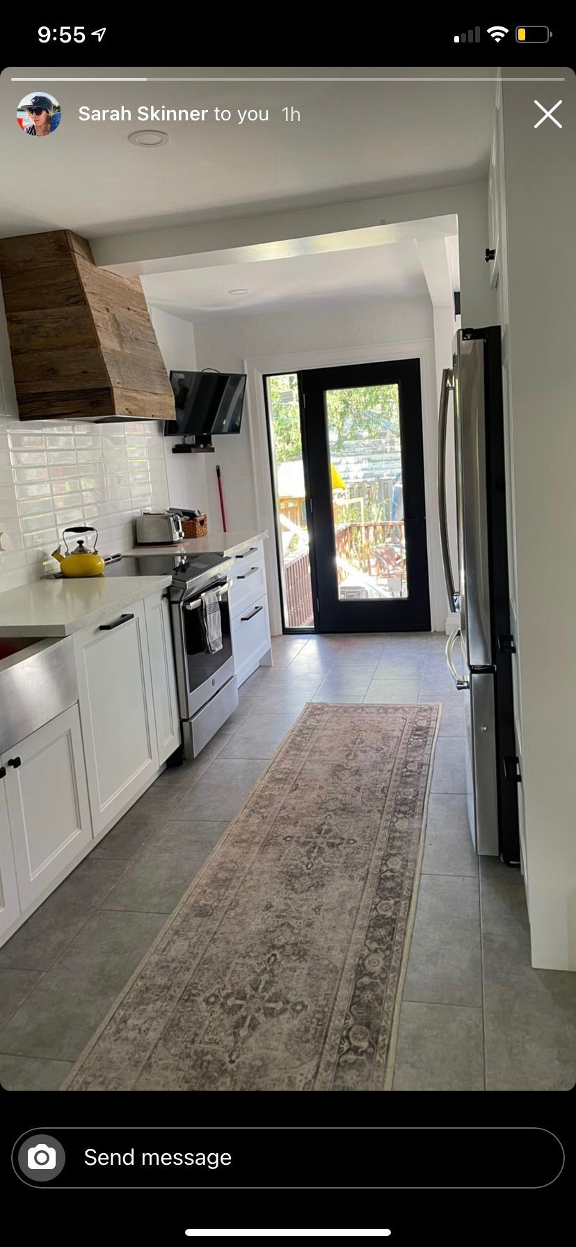A kitchen with white cabinets , stainless steel appliances , a rug and a door.