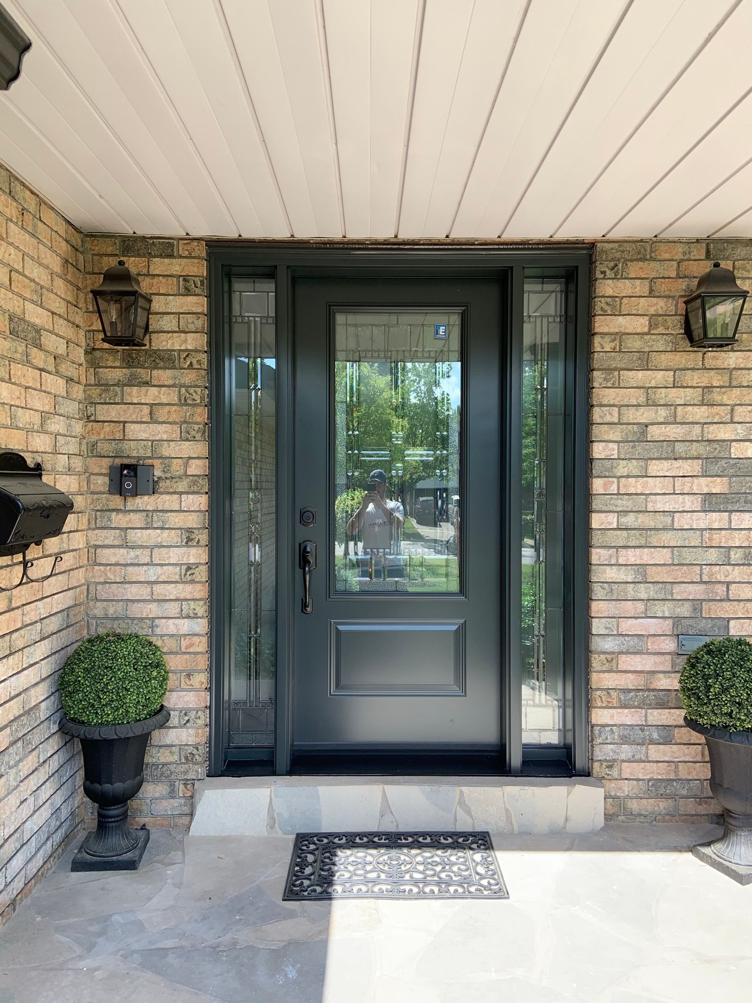 The front door of a brick house with a black door.