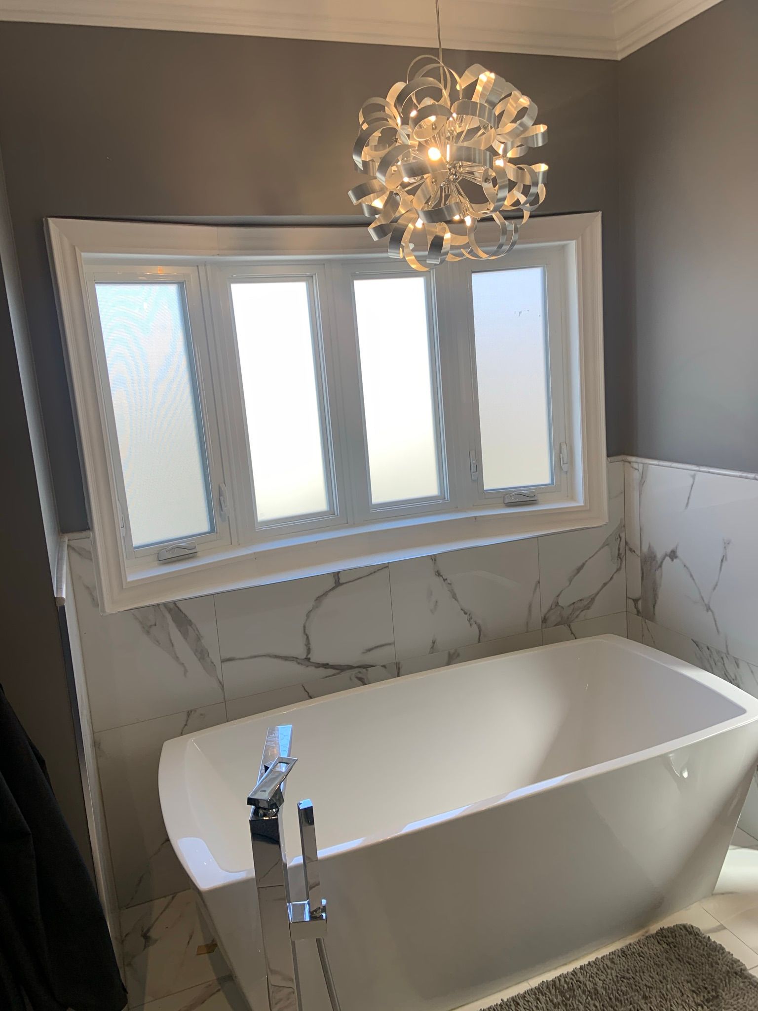 A bathroom with a bathtub and a chandelier hanging from the ceiling.