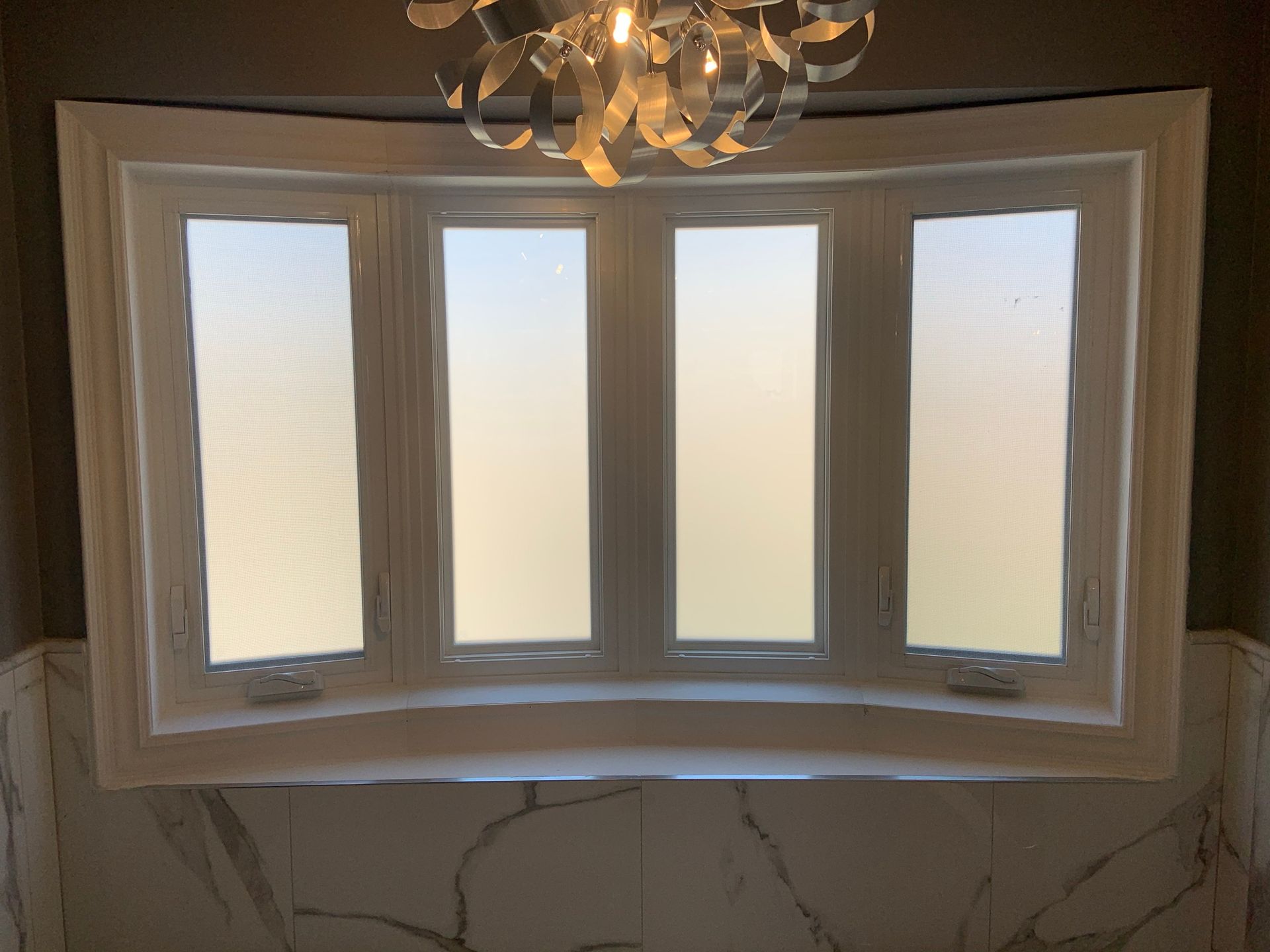 A bathroom with a large window and a chandelier hanging from the ceiling.