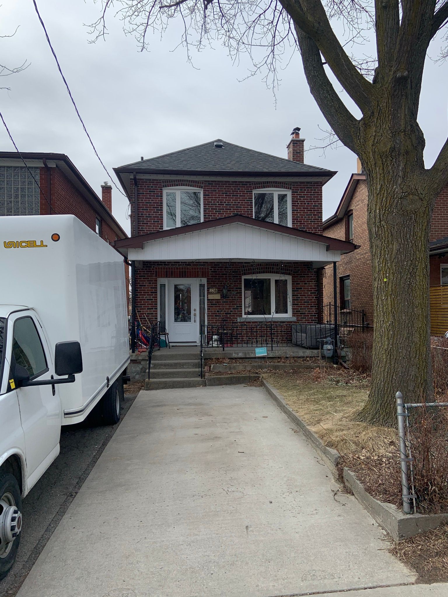 A white truck is parked in front of a brick house.