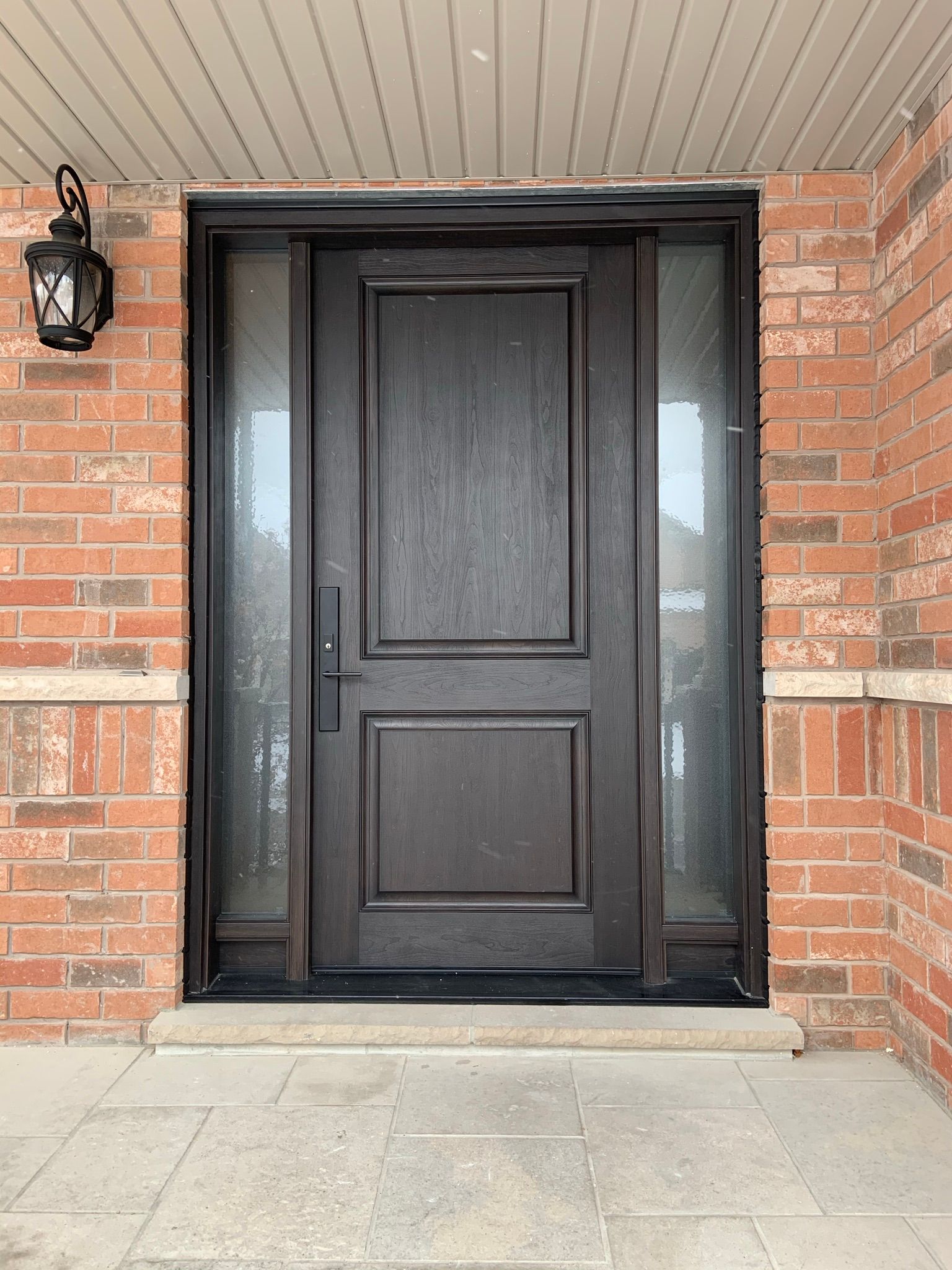 A black front door is sitting on top of a brick wall.