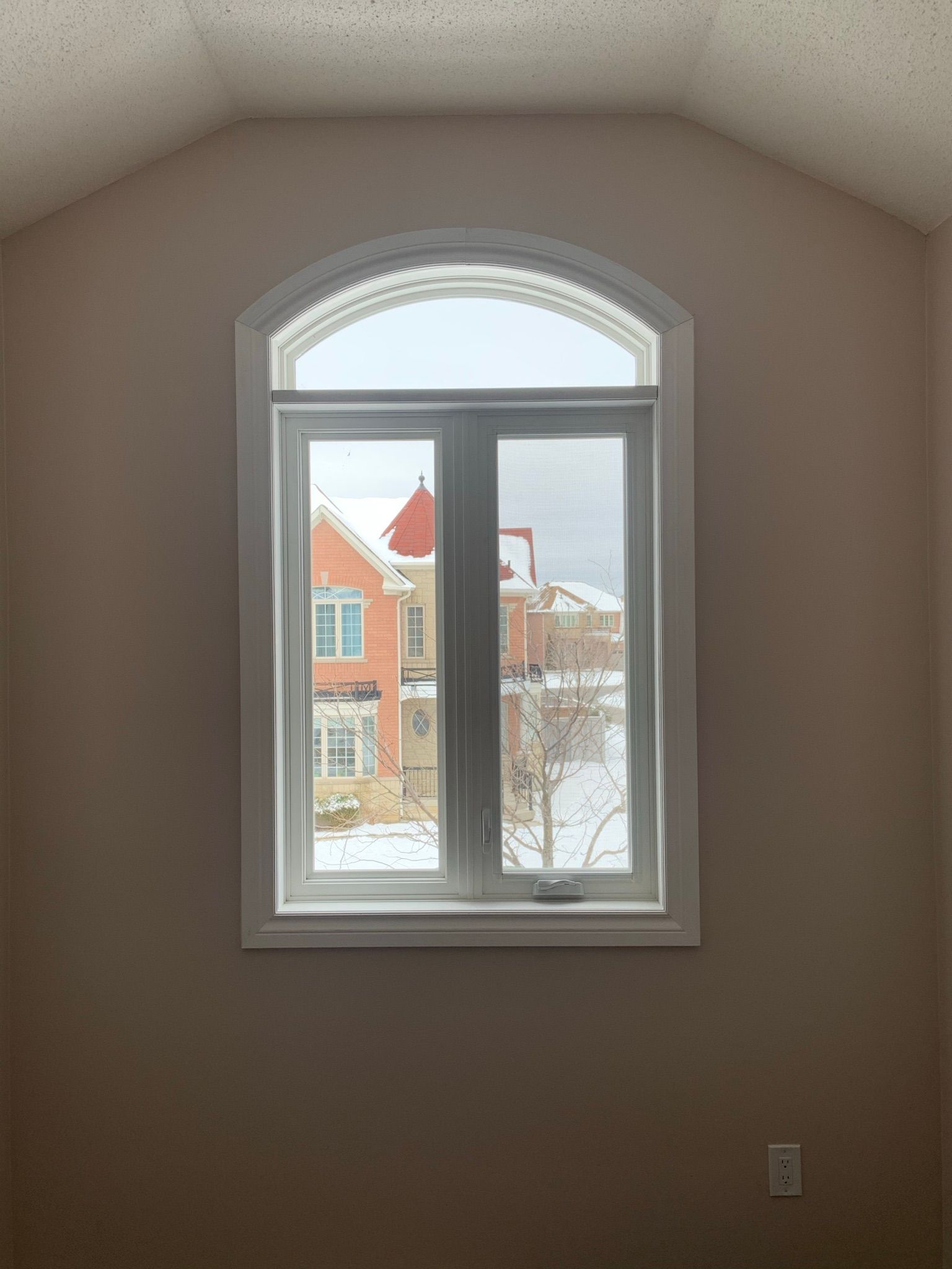 A window in a room with a view of a snowy yard.
