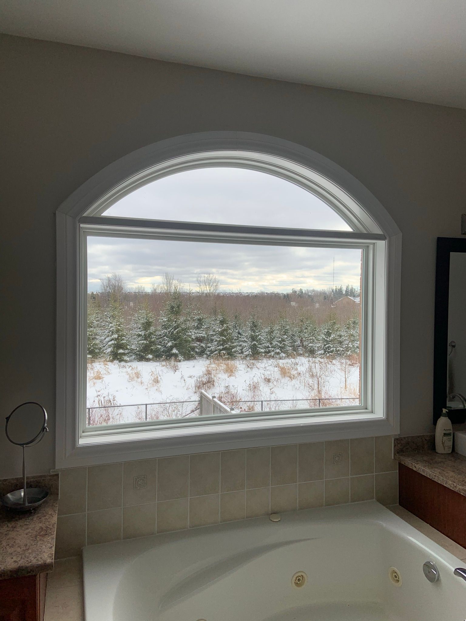 A bathroom with a tub and a window with a view of a snowy field.