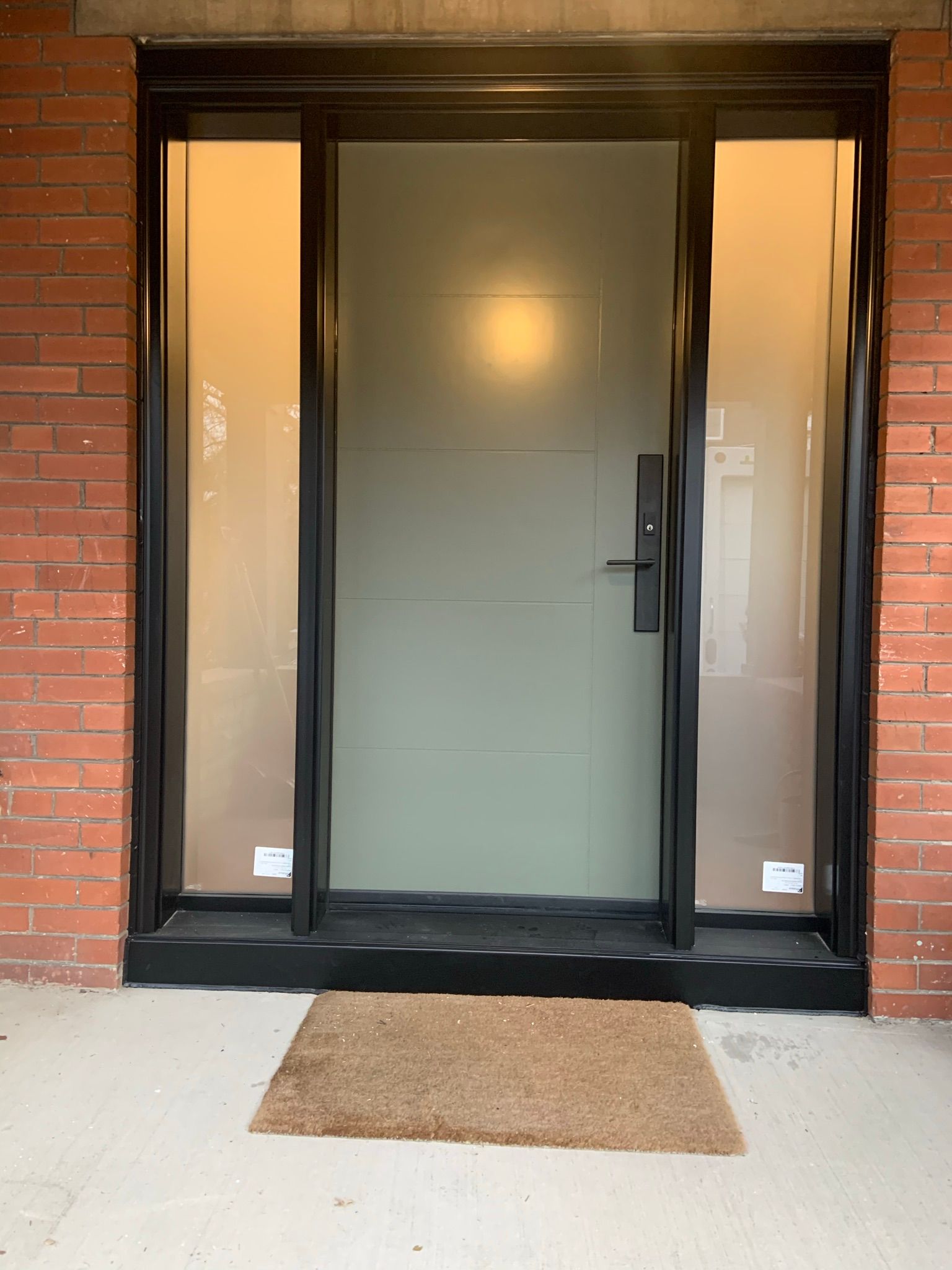 A brick building with a black door and a door mat