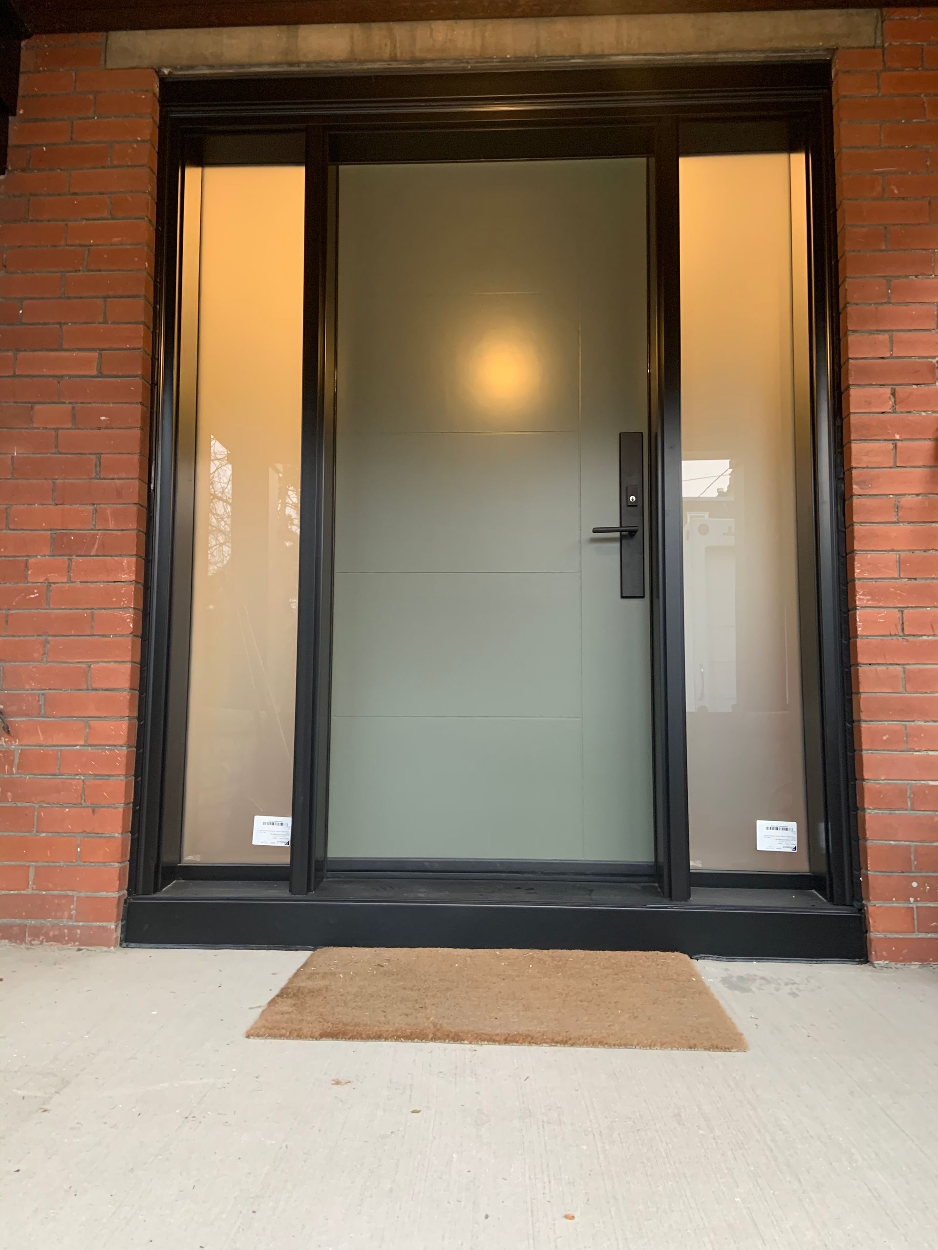 The front door of a brick house with a door mat in front of it.