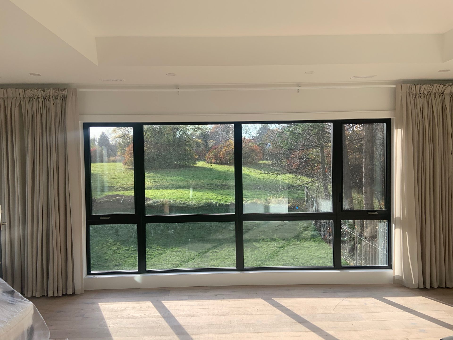 There is a large window in the middle of the room with a view of a field.