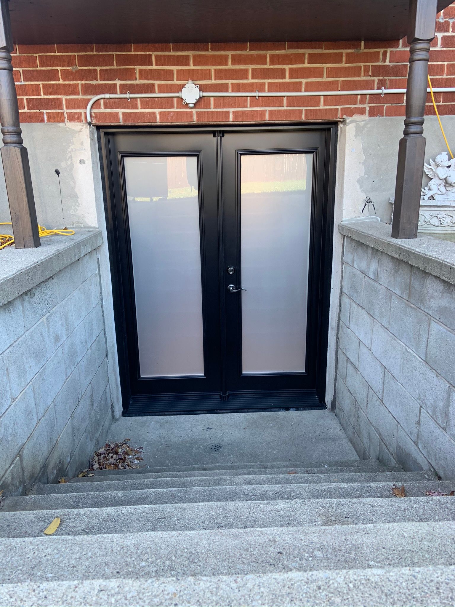 A brick building with a black door and stairs leading up to it.