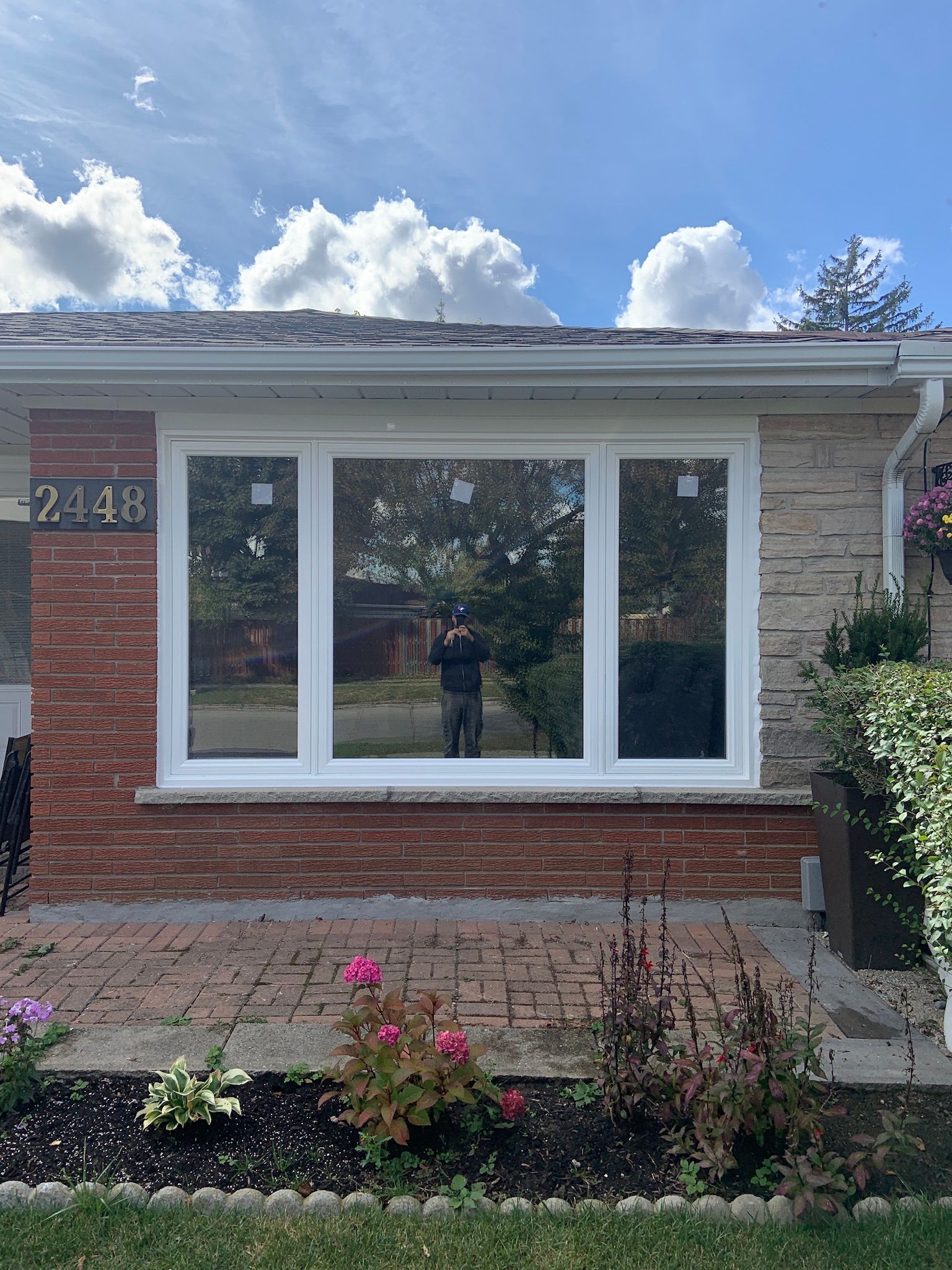 A brick house with a white window and a garden in front of it.