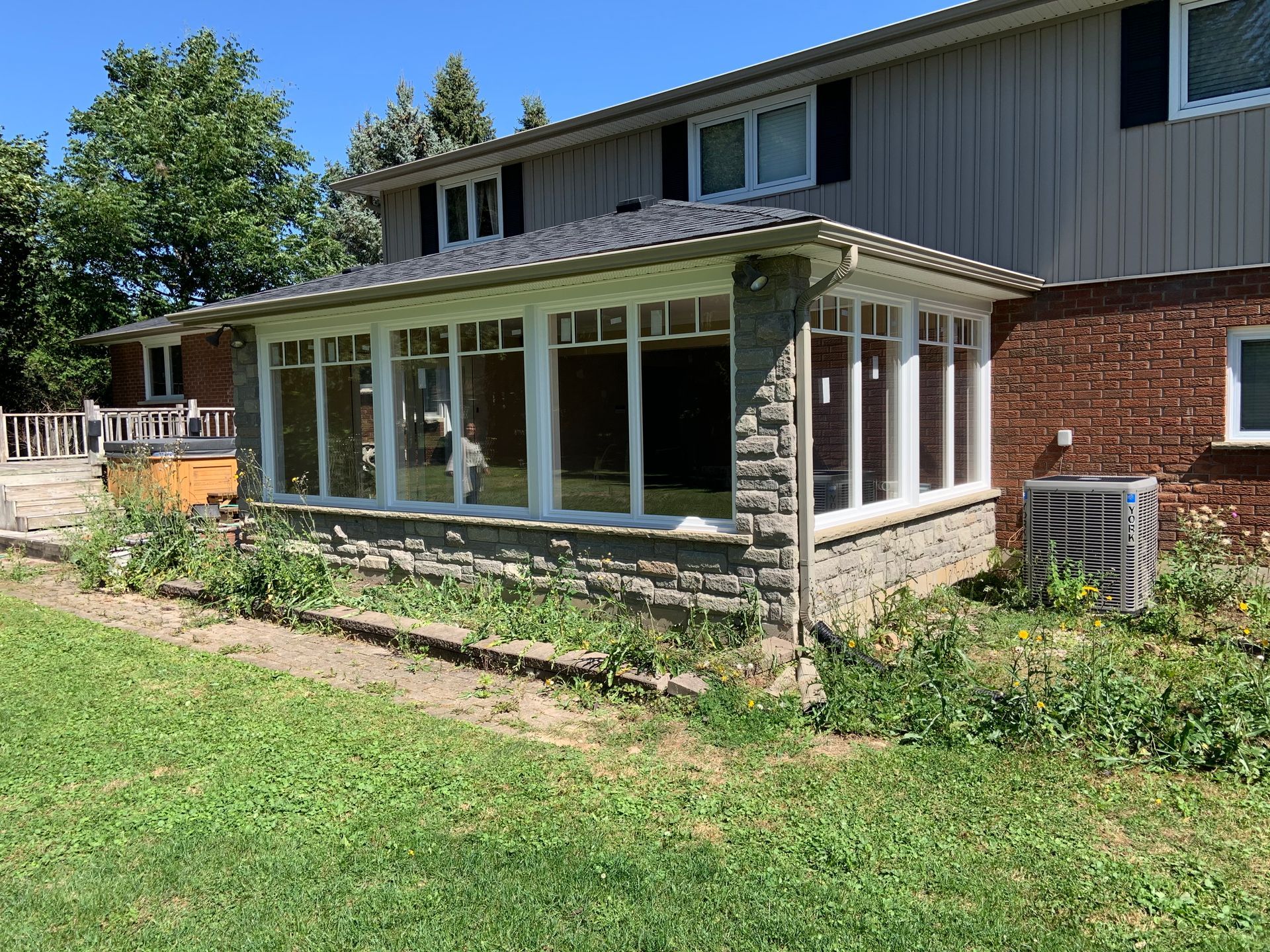 A house with a screened in porch and a large lawn in front of it.