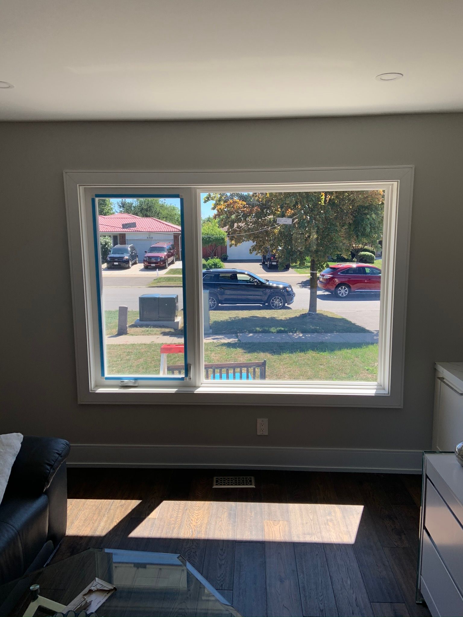 A living room with a large window looking out to a street.
