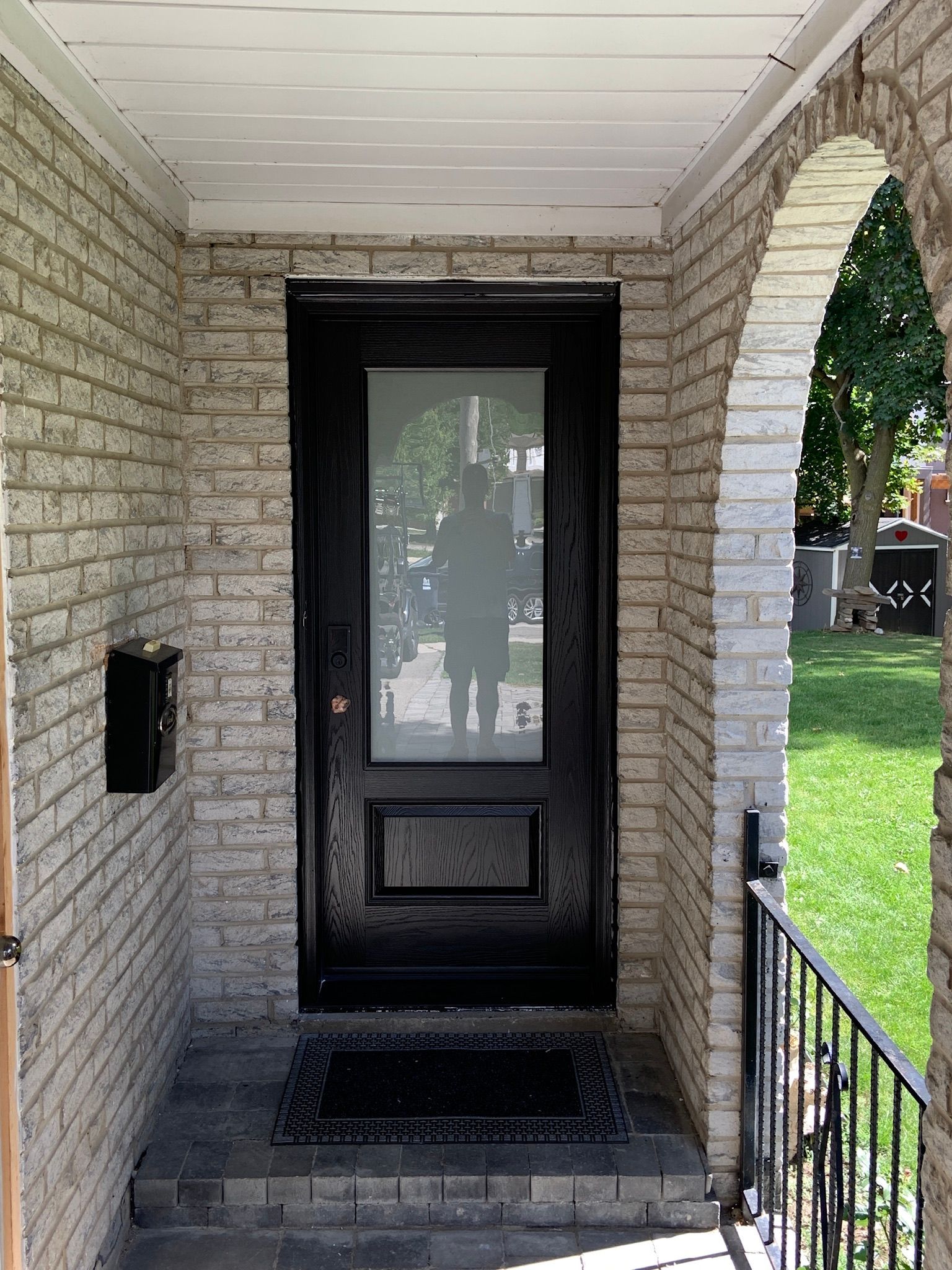 The front door of a white brick house with a black door.