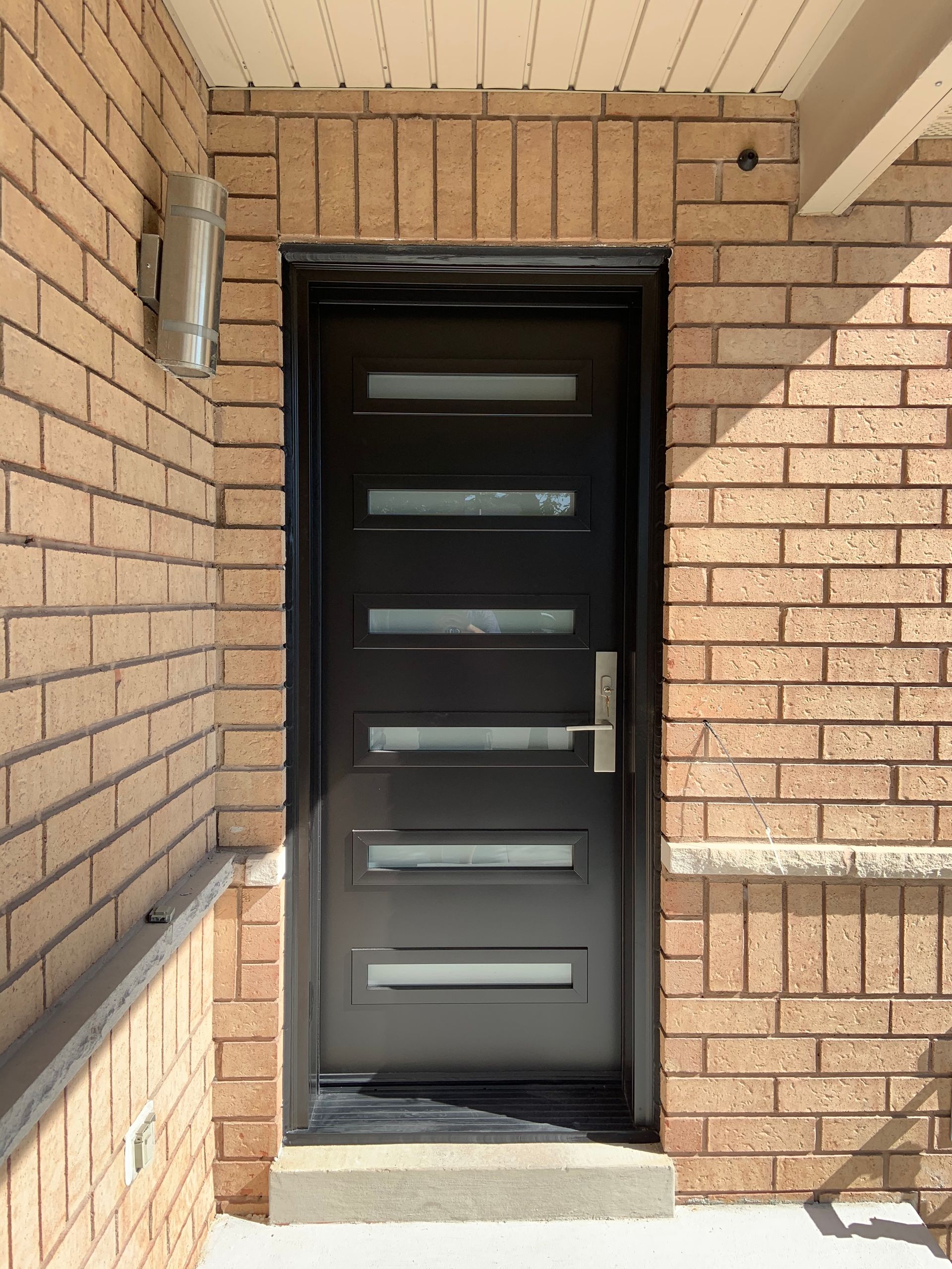 A black door is sitting on top of a brick wall.