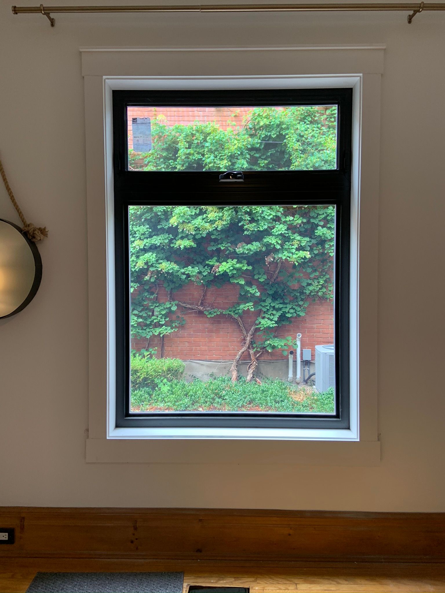 A window with a view of a brick wall and trees in a living room.