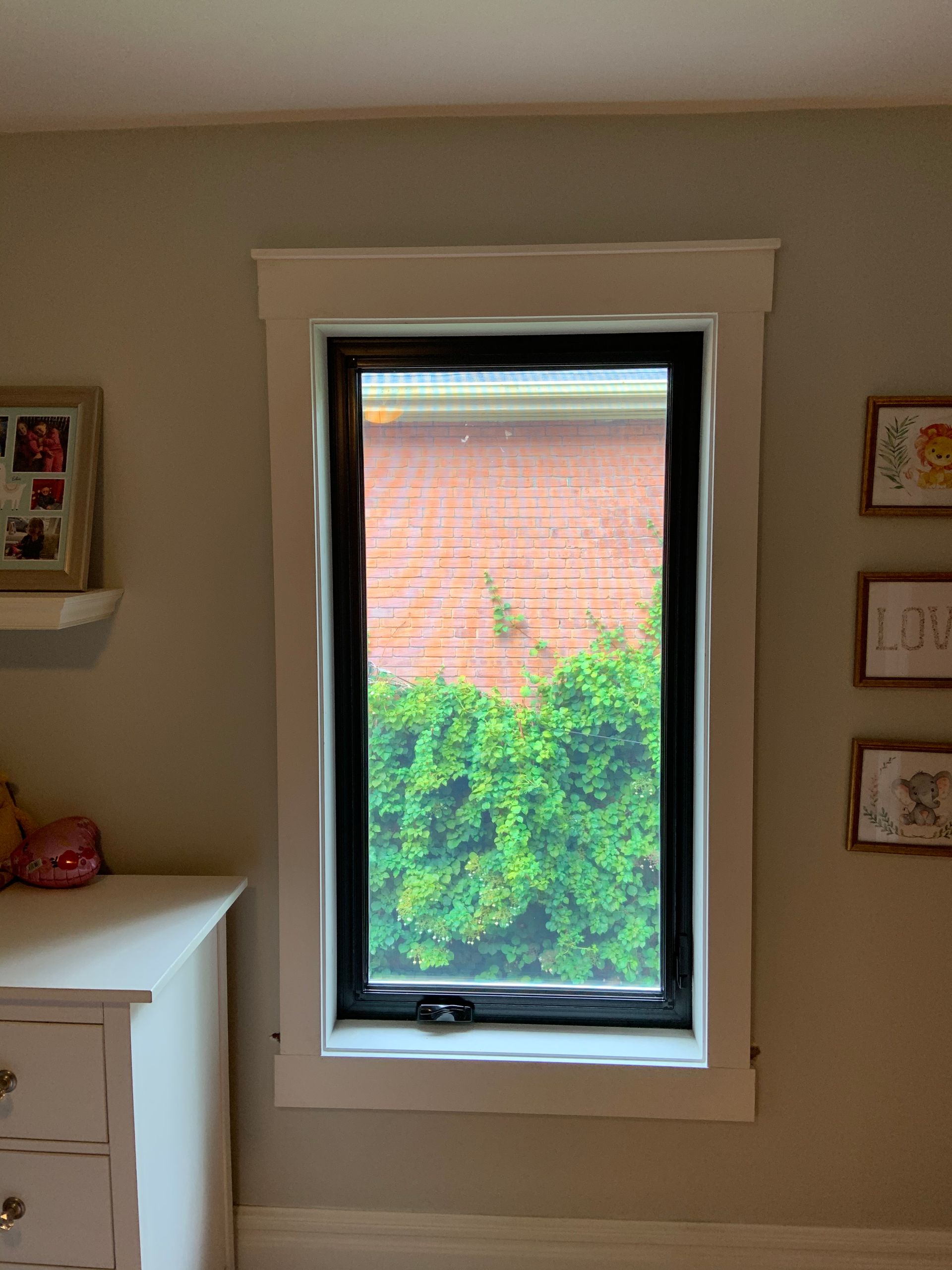 A bedroom with a large window and a dresser.