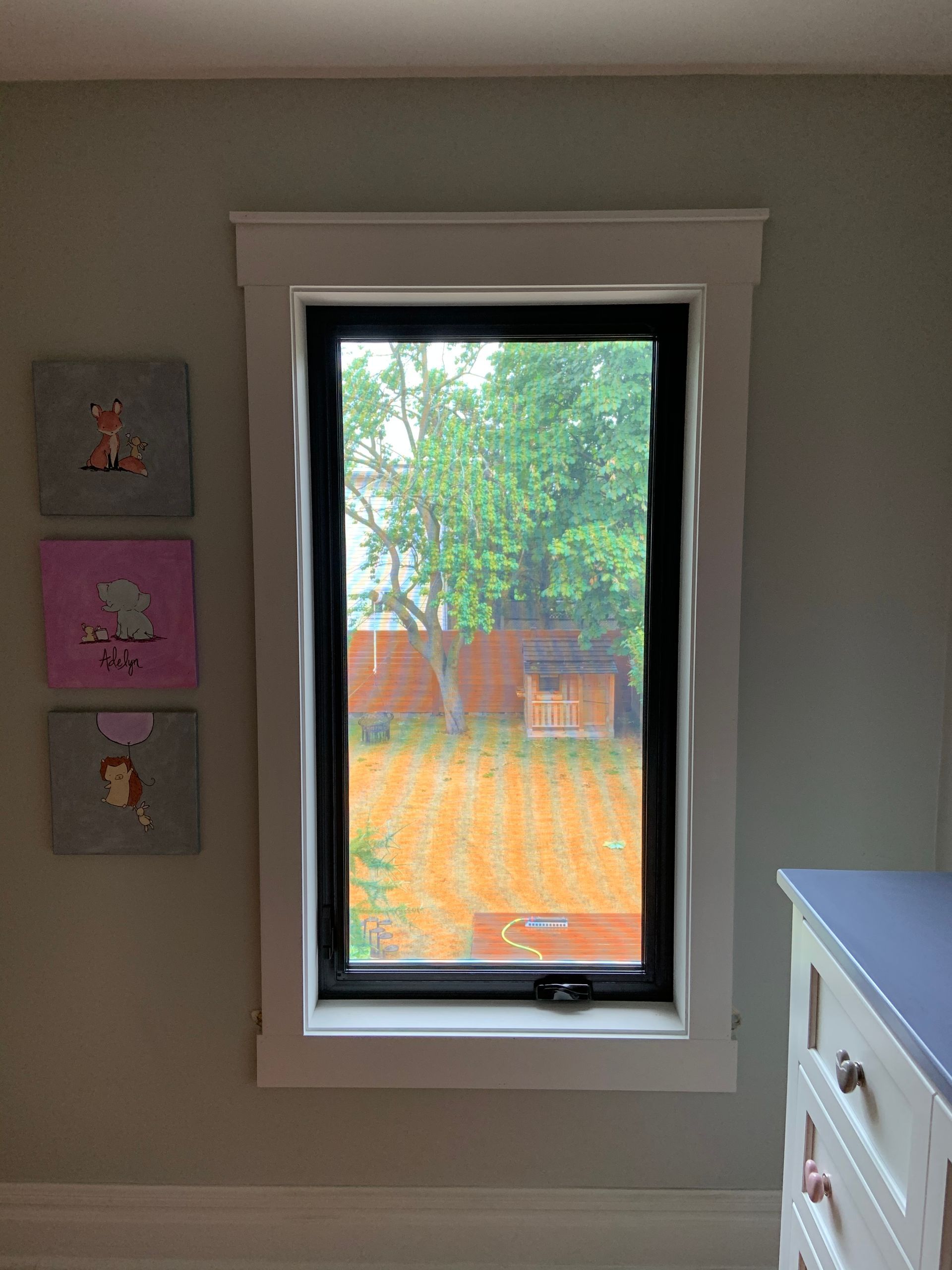 A bedroom with a large window and a dresser.