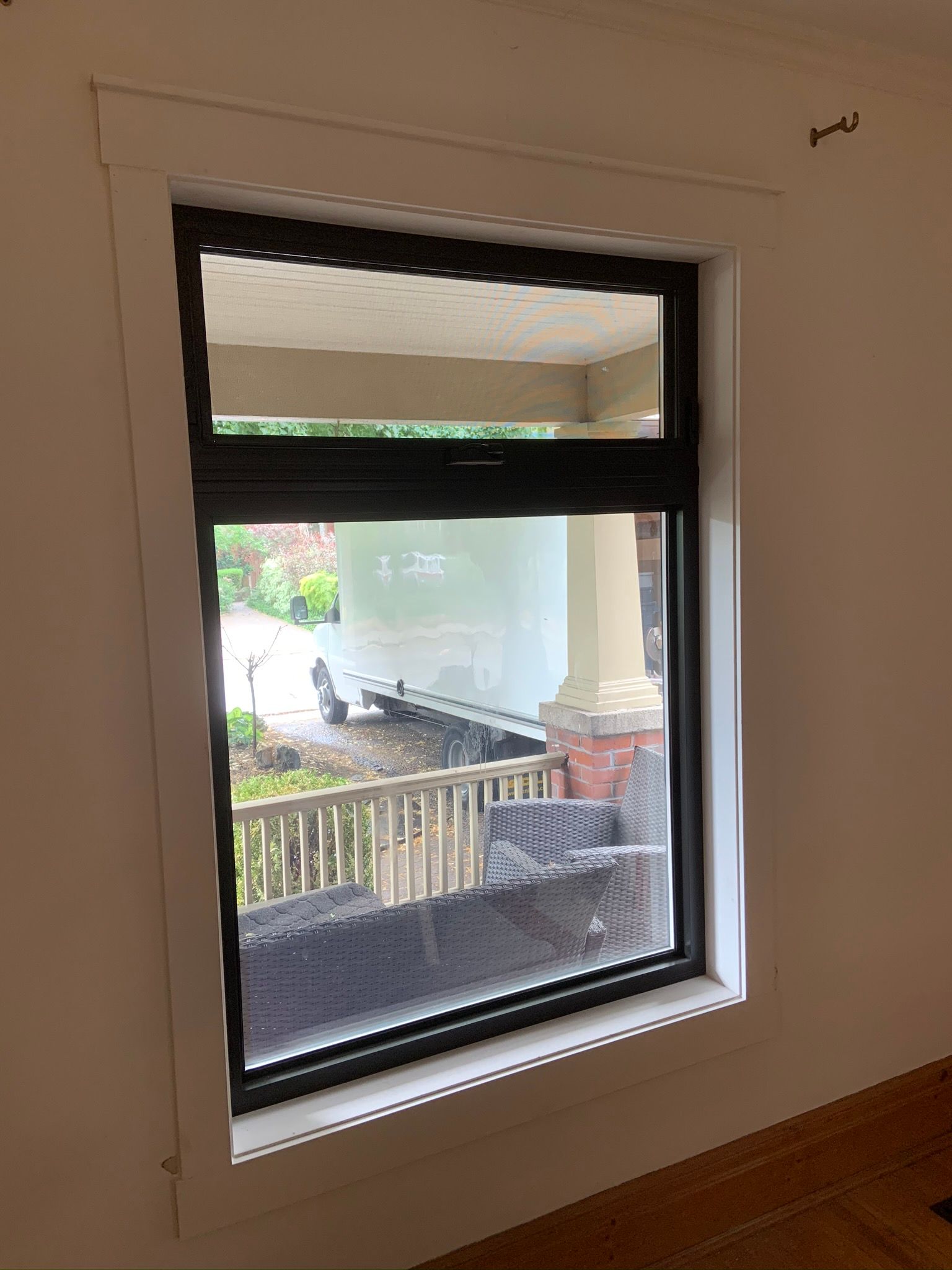A large window in a room with a view of a porch and a truck.