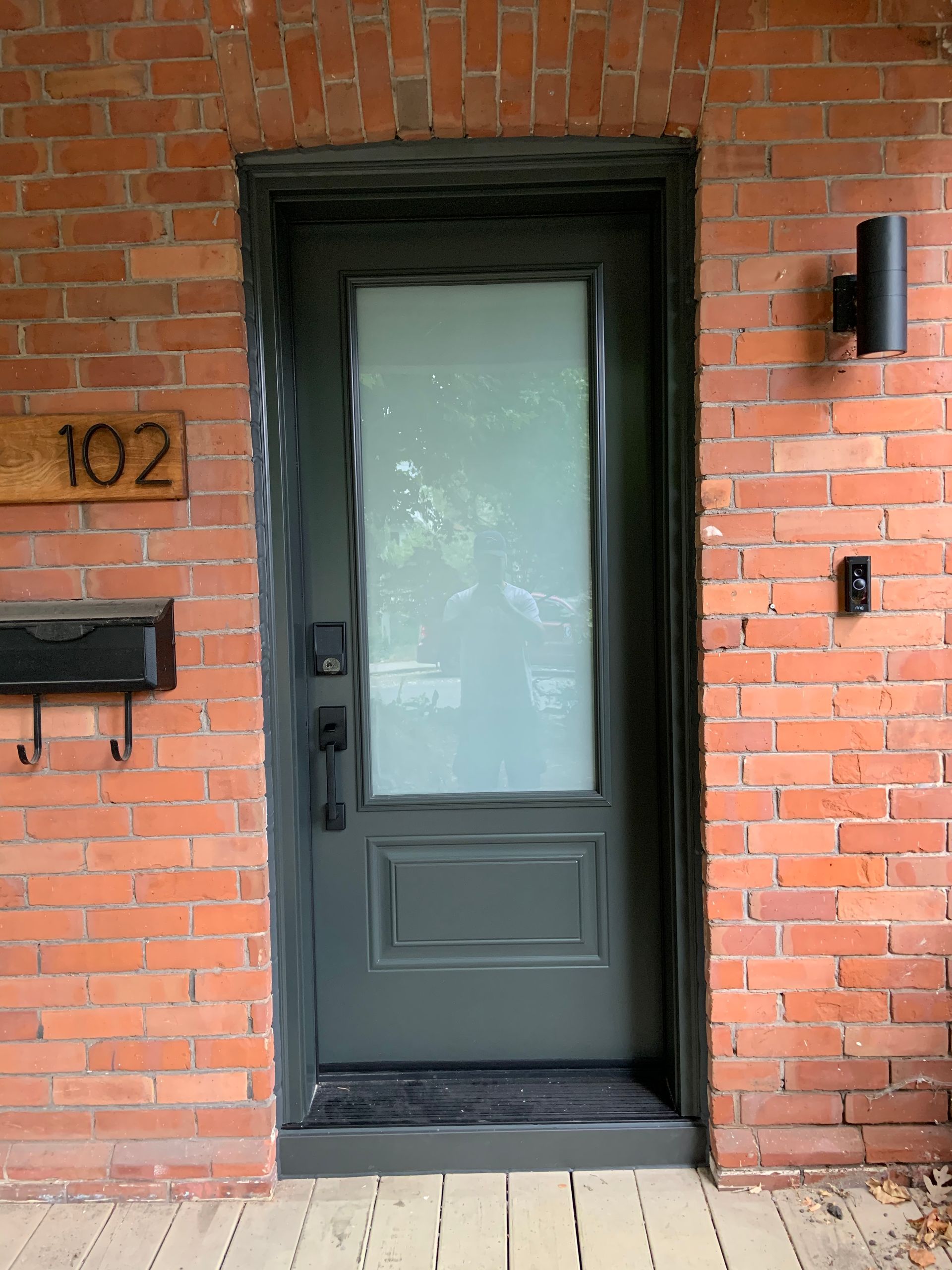 A brick building with a black door and a mailbox.