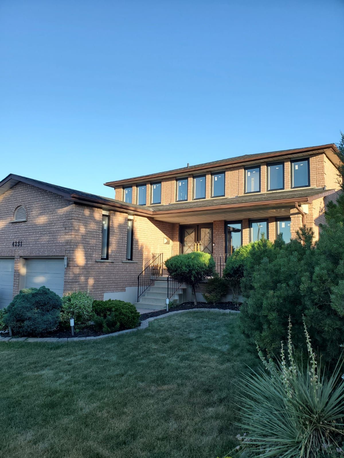 A large brick house with a large lawn in front of it.