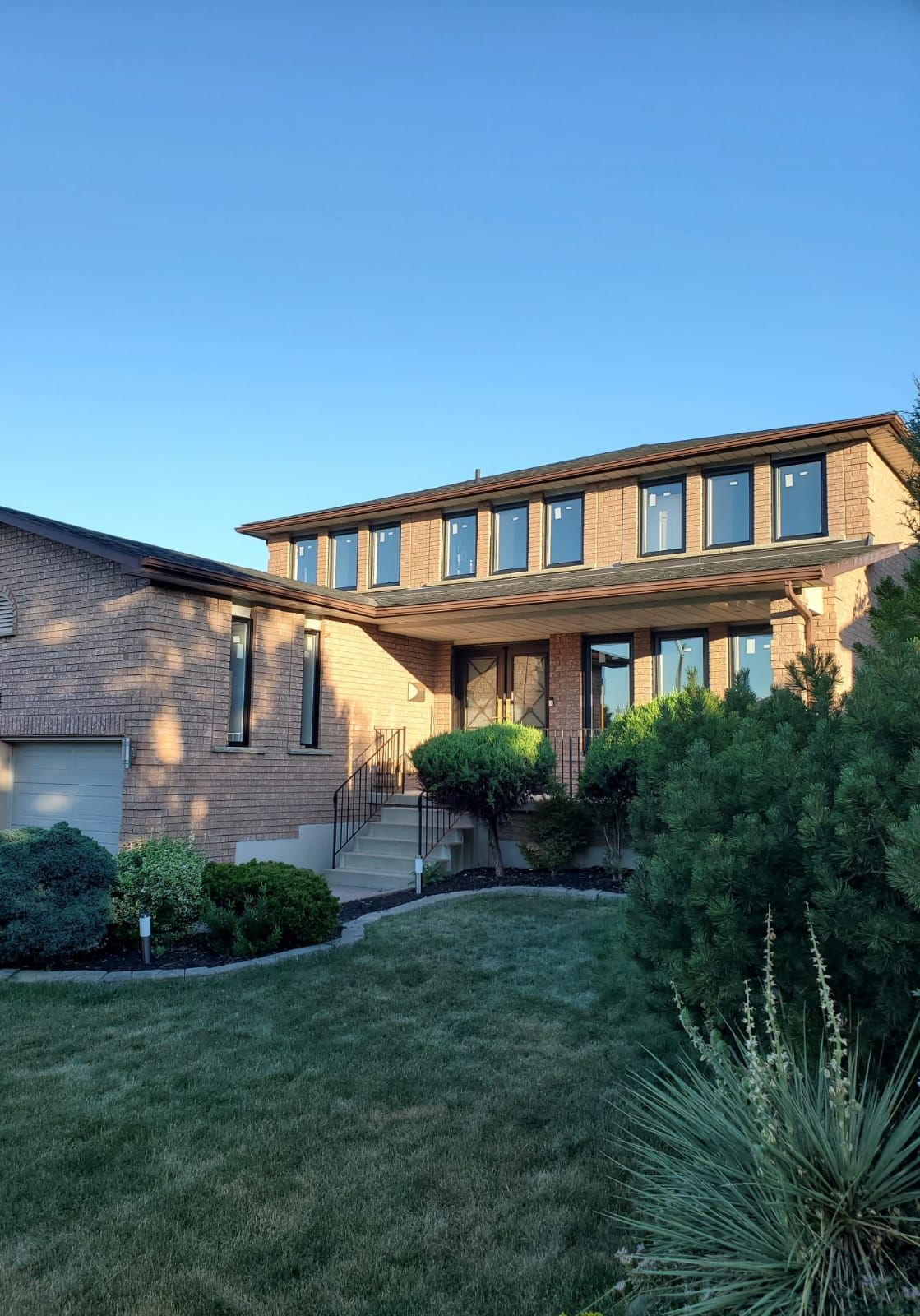 A large brick house with a lot of windows and a large lawn in front of it.