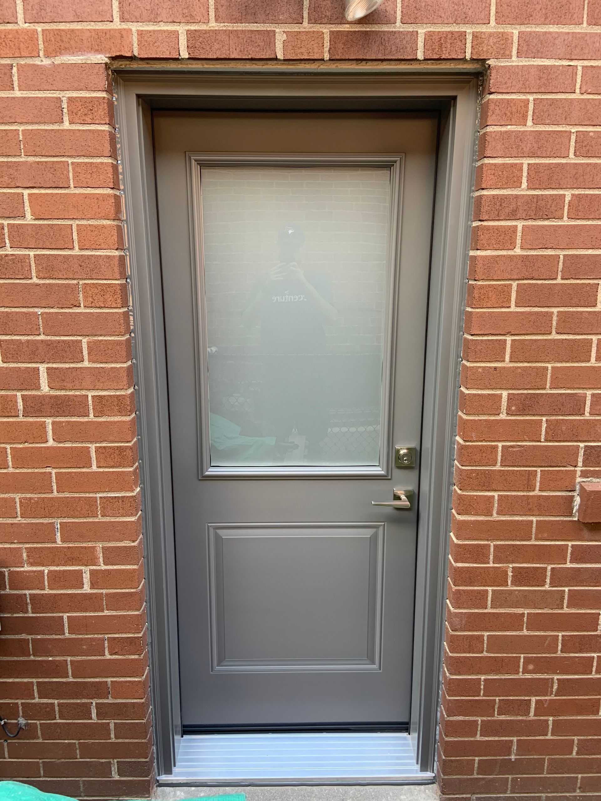 A gray door is sitting on a brick wall.