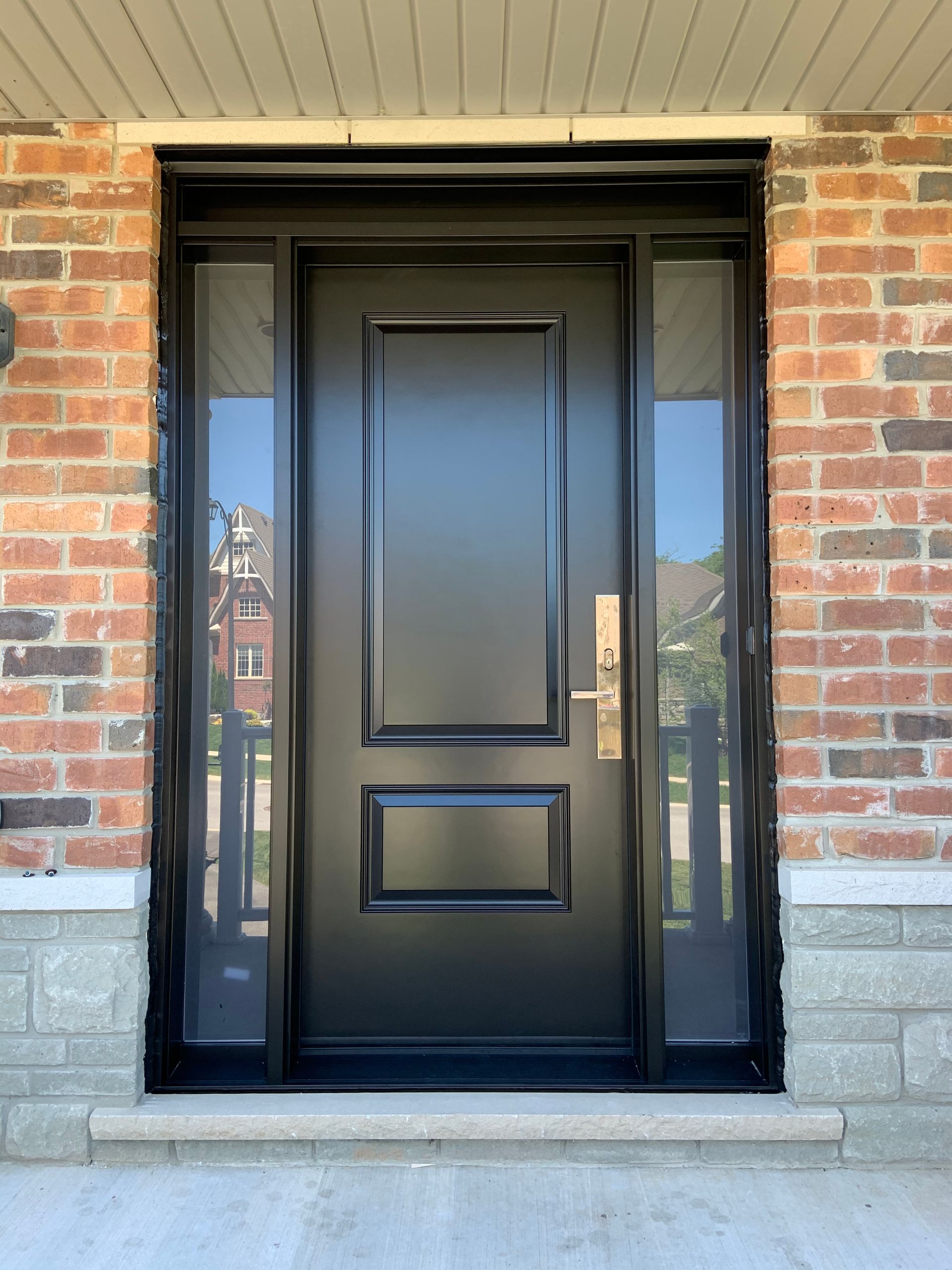 A black door is sitting on a brick wall.