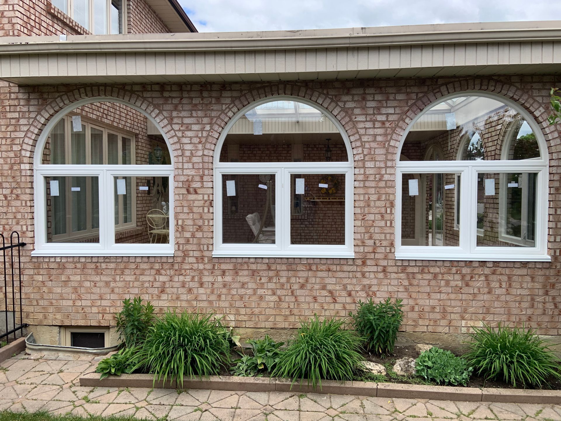 A brick building with arched windows and a garden in front of it.