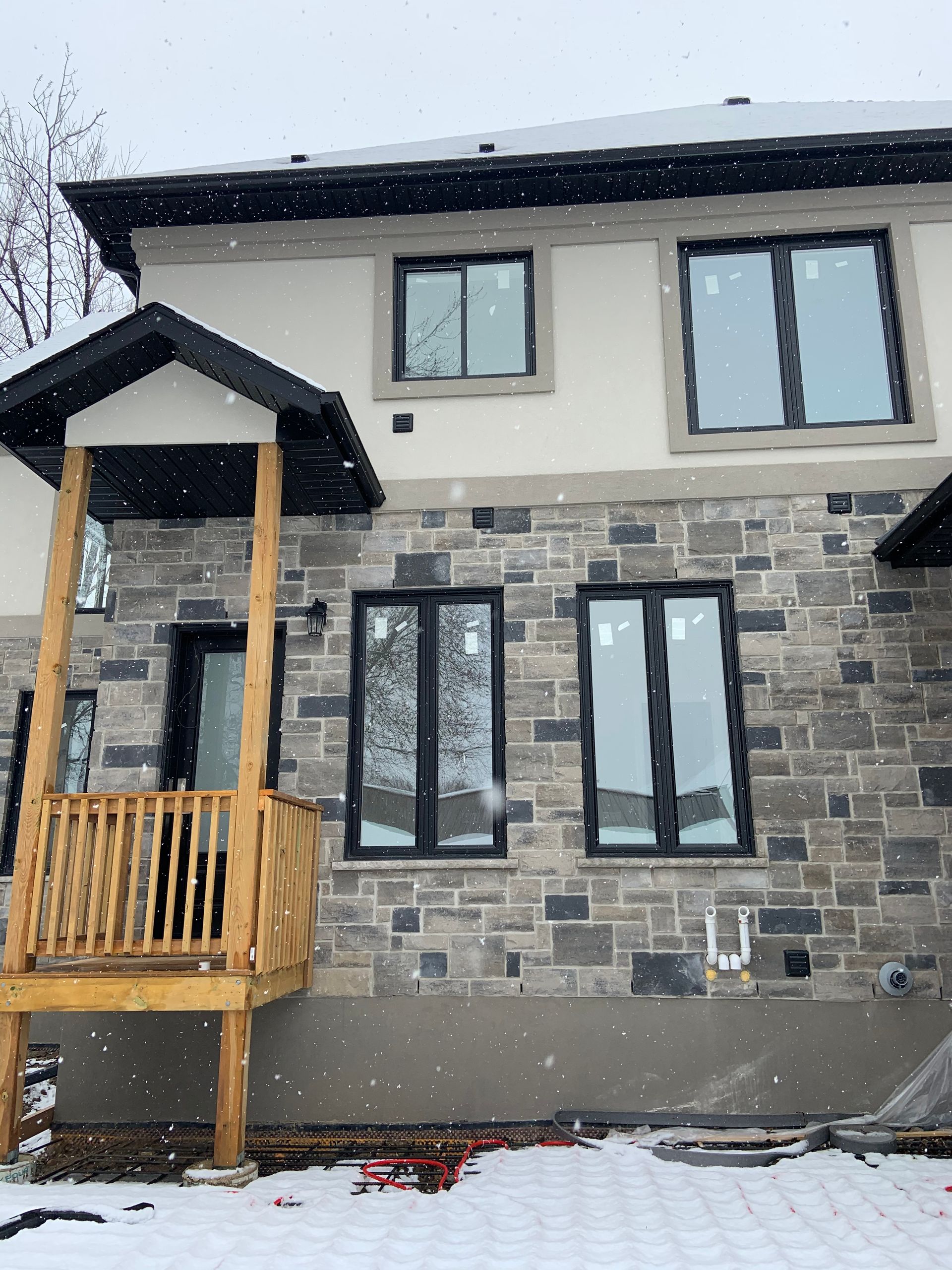 A house with a porch and a lot of windows is covered in snow.