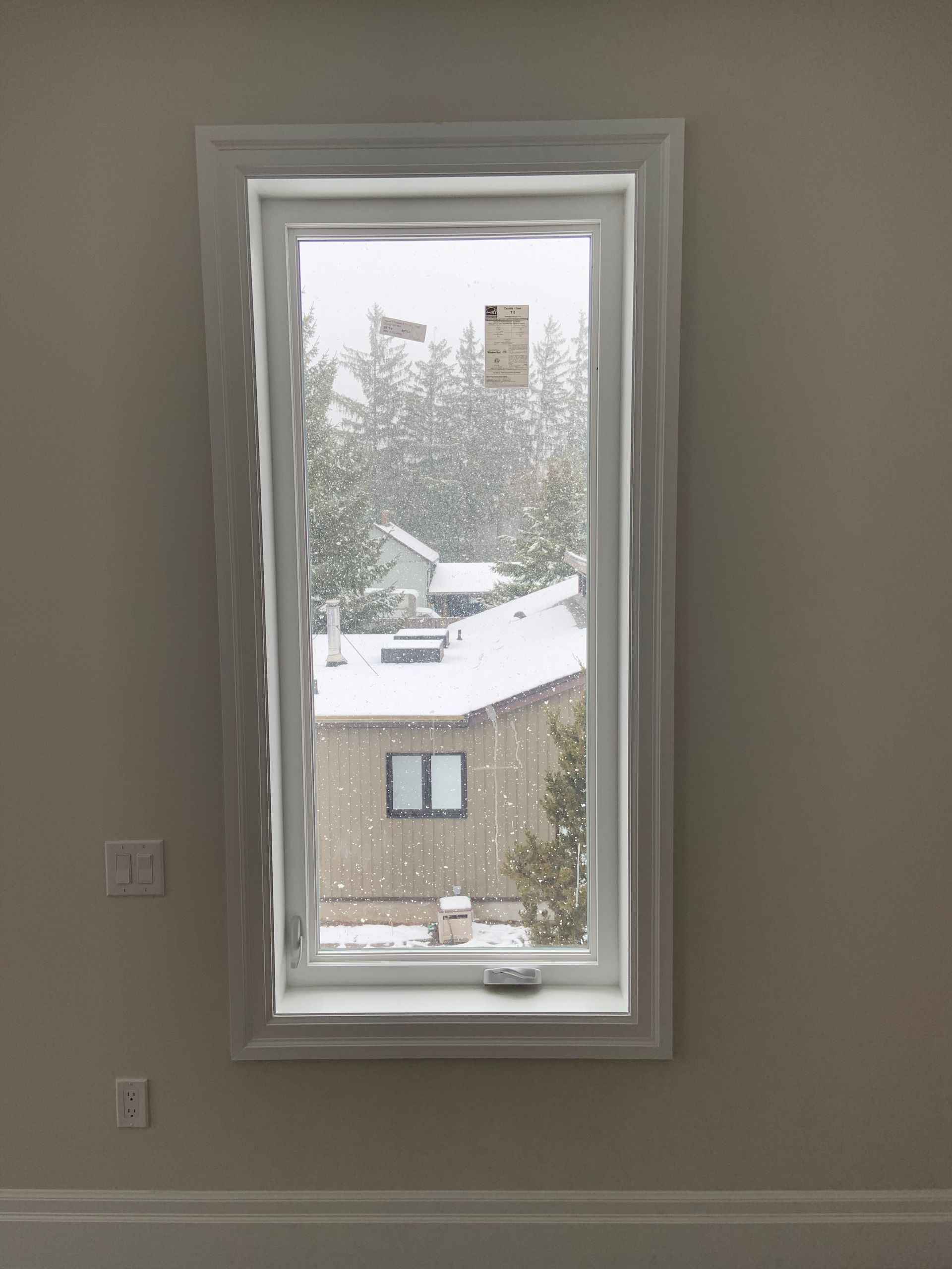 A window in a room with a view of a snowy house.