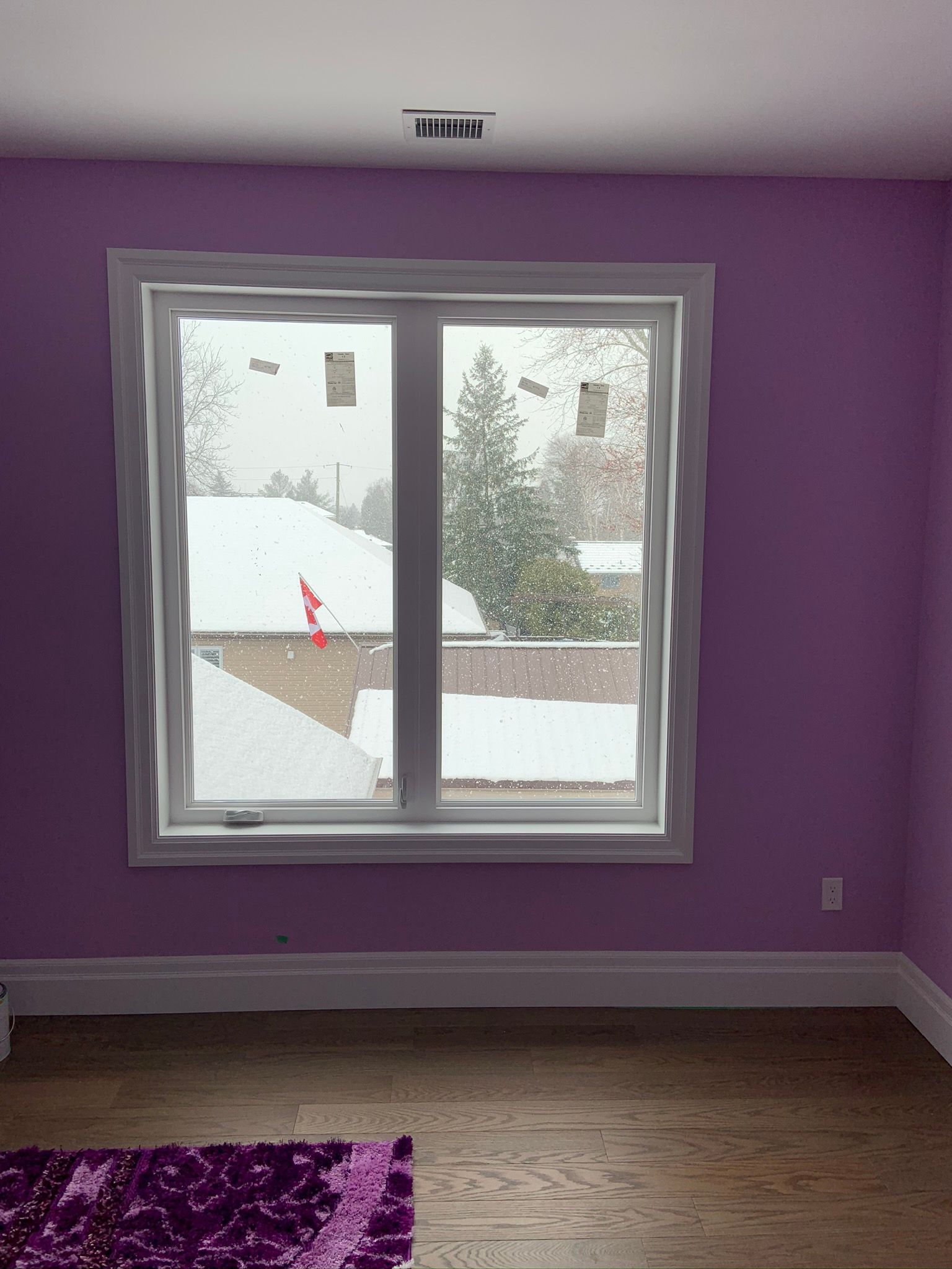 A room with purple walls and a window with snow on the roof