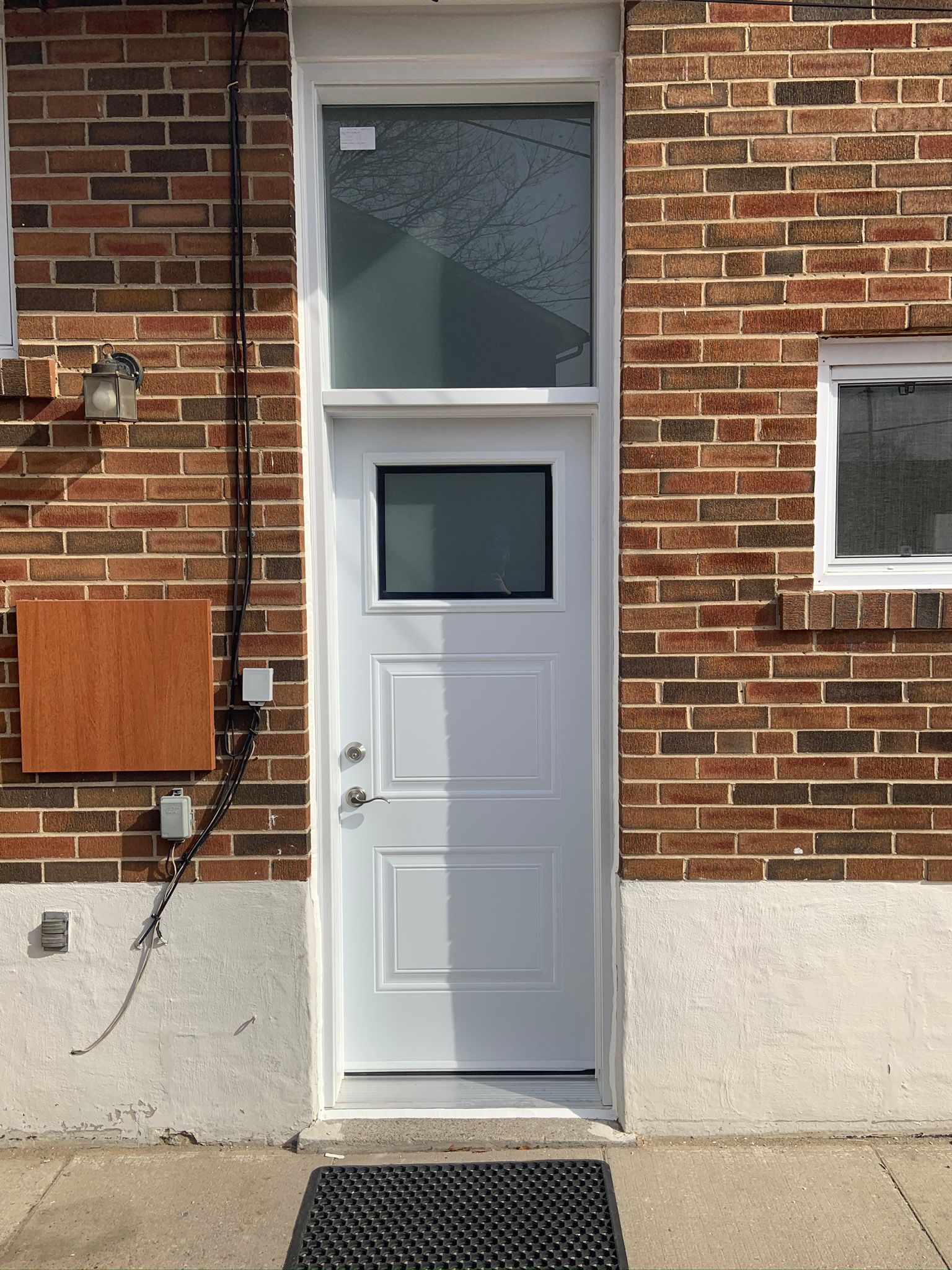 A white door is sitting on the side of a brick building.
