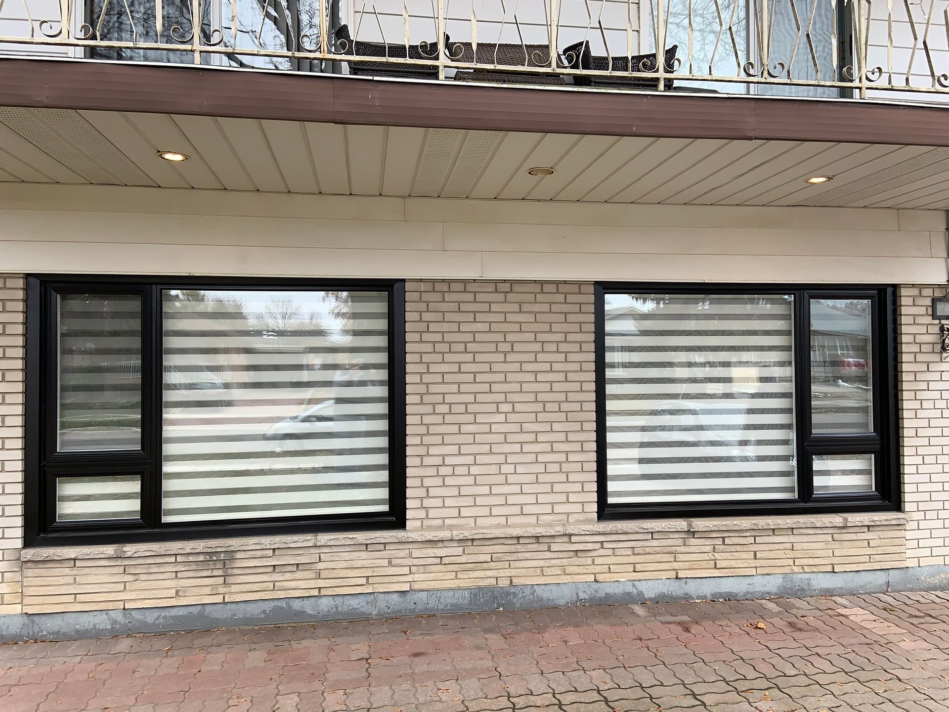 A brick building with two windows and a balcony.