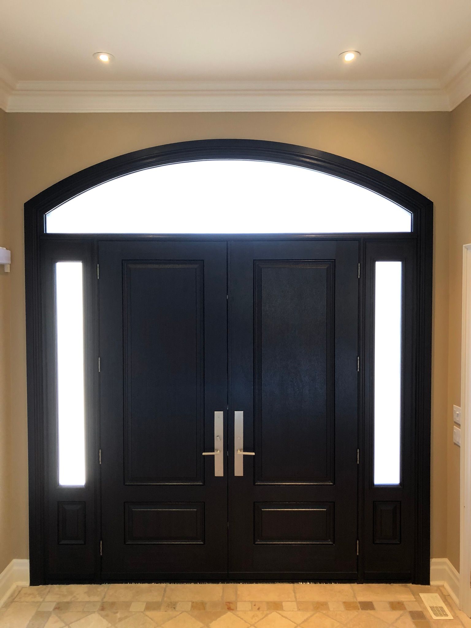 A large black door with arched windows in a hallway