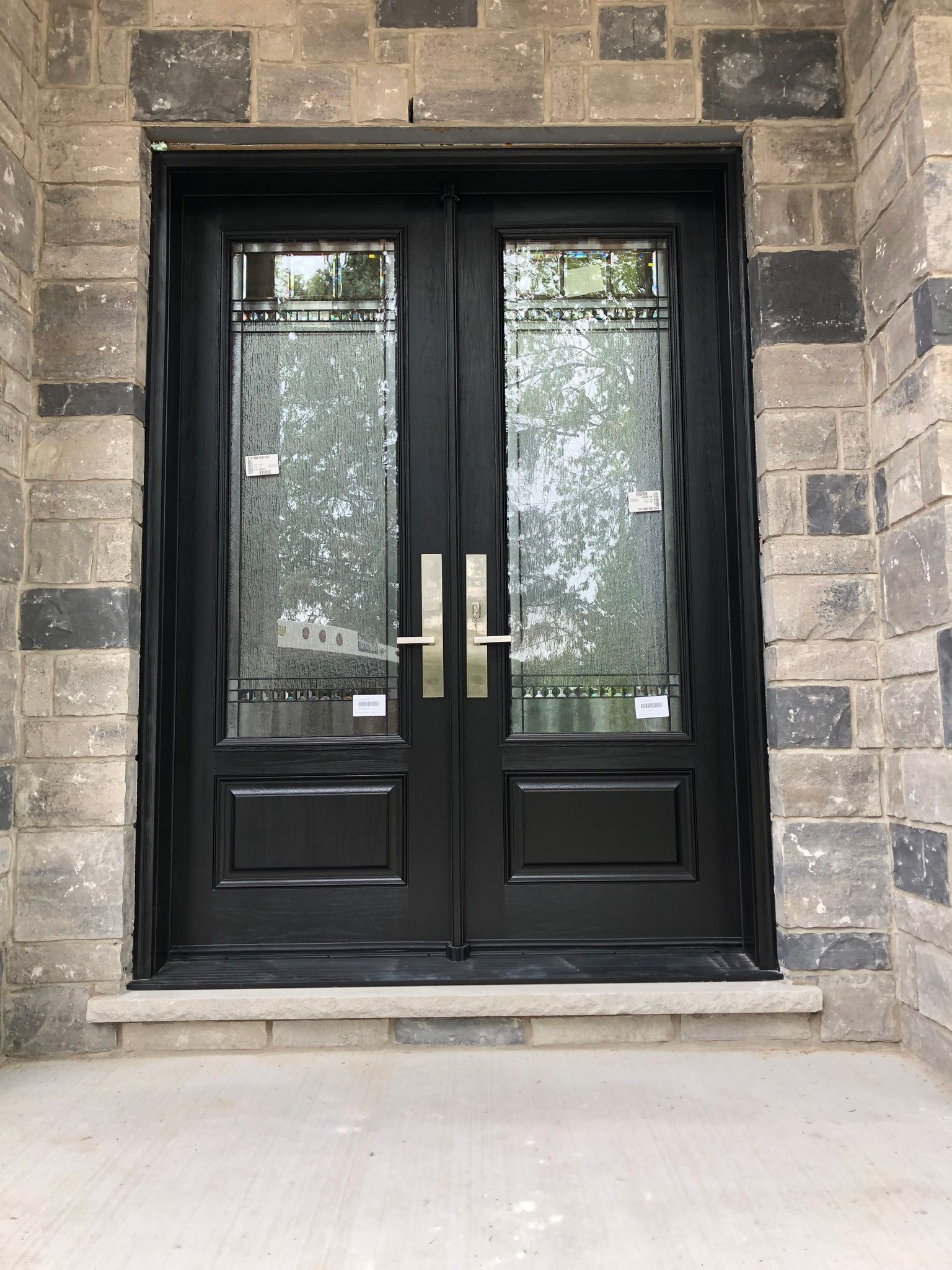 A pair of black double doors on a brick wall.
