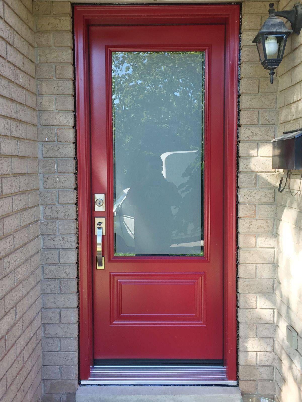 A red door with a glass window on a brick wall