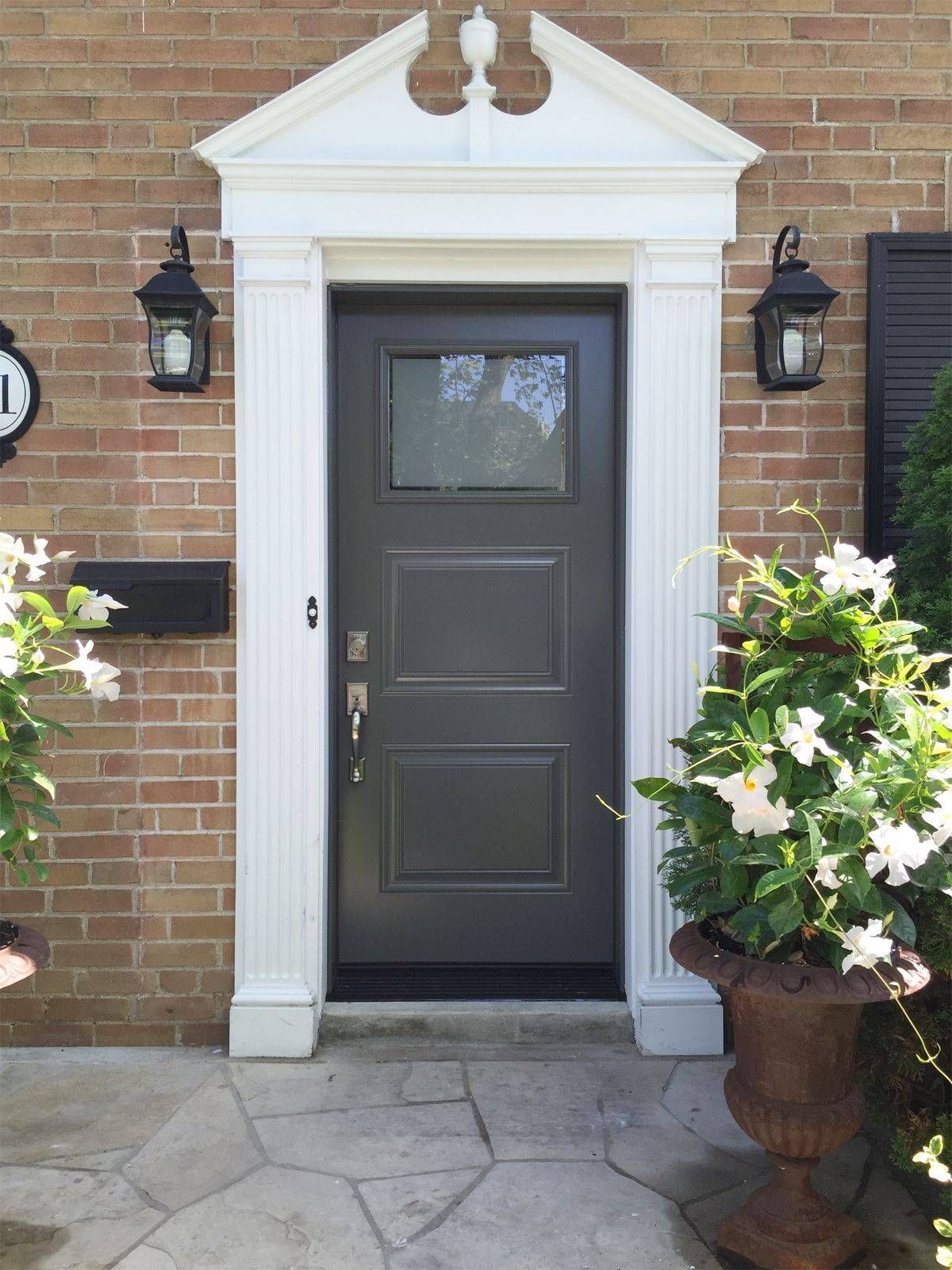 A brick house with a gray door and white trim