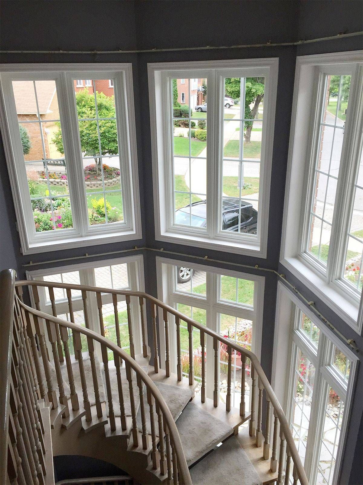 A spiral staircase in a house with lots of windows.