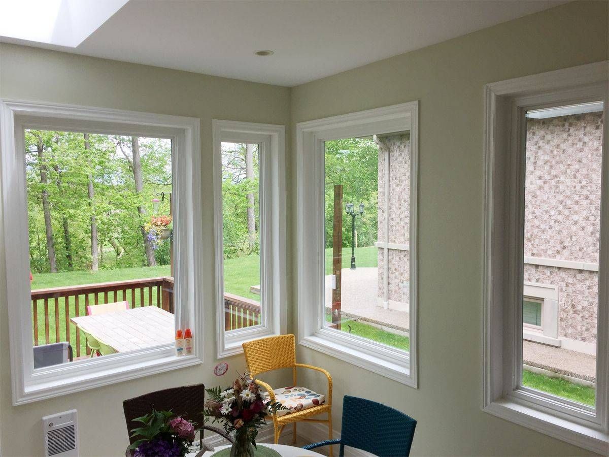 A dining room with a table and chairs and a lot of windows.