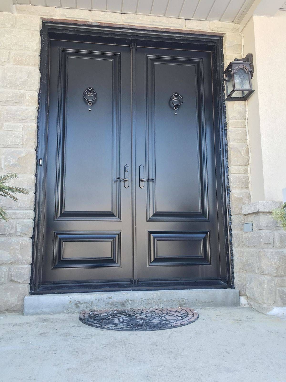 A black double door with a lamp on the side of it