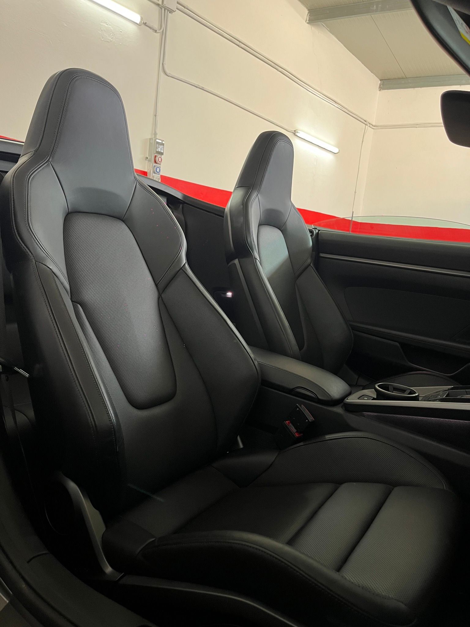Sedili in pelle nera all'interno di un veicolo, poggiatesta grigi, ambiente interno.