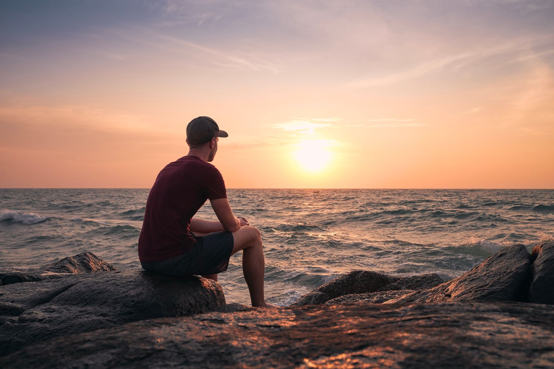 Homem admirando por do sol na praia.