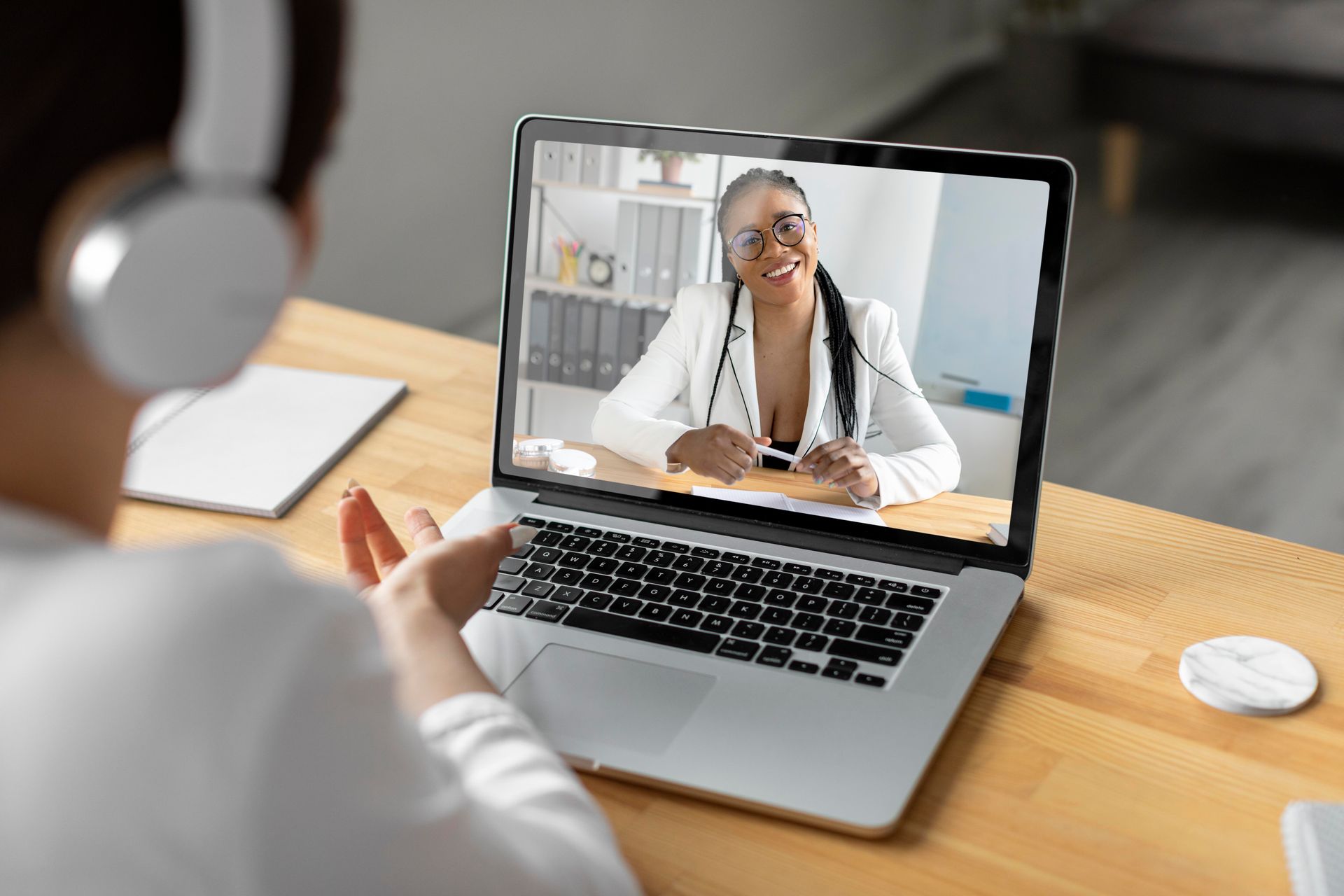 Chamada de vídeo em um laptop com um médico sorridente de jaleco branco.