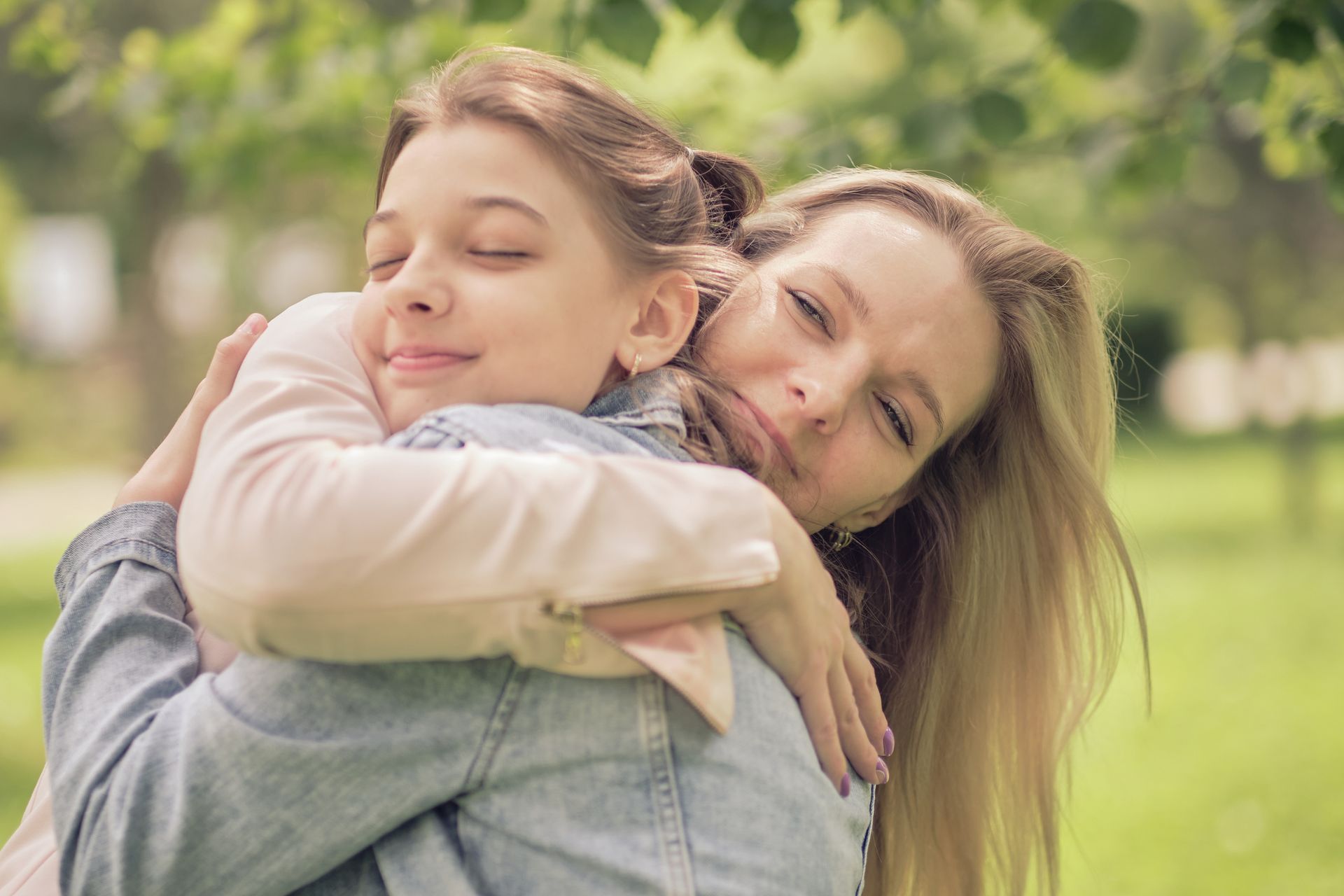 Mãe e filha se abraçando em parque.