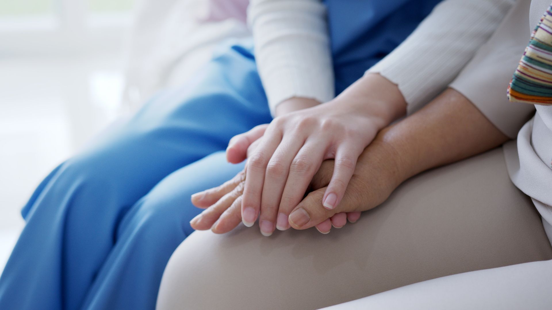 Duas mulheres de mãos dadas sentadas no sofá.
