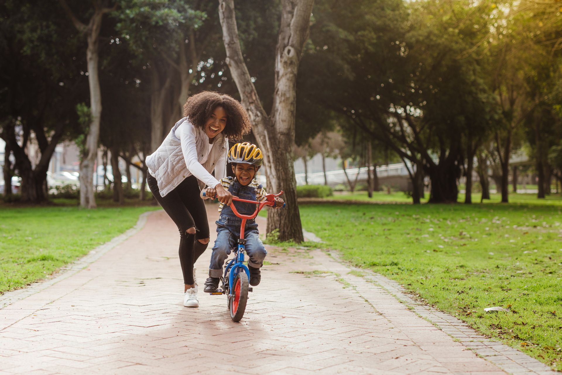 Uma mulher ensinando uma criança a andar de bicicleta em um parque