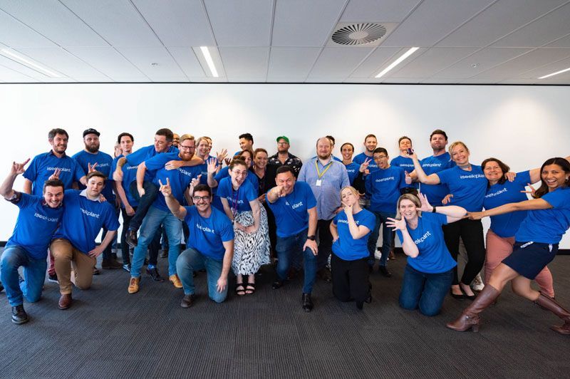 a large group of people wearing blue shirts are posing for a picture .